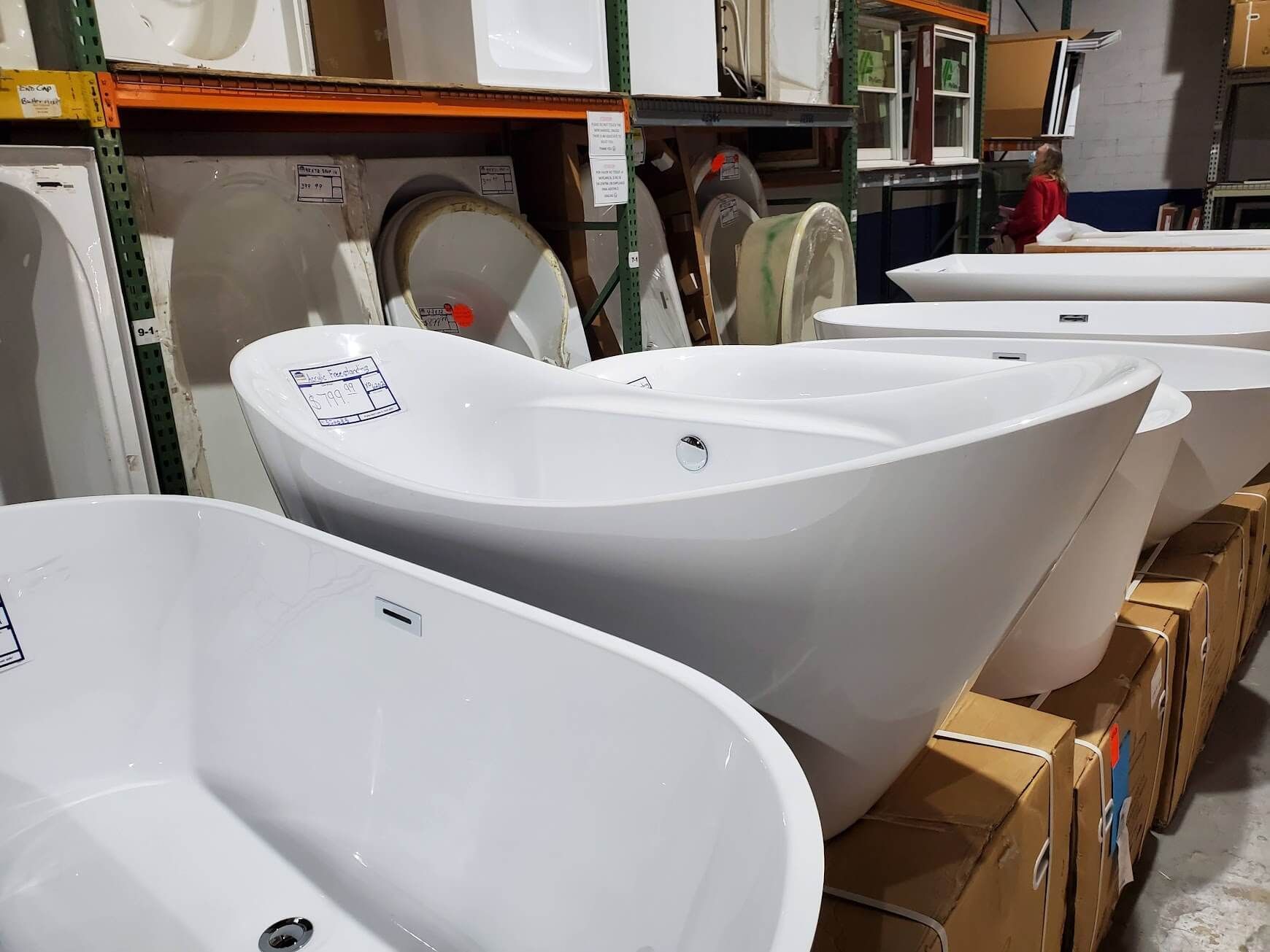 A warehouse filled with lots of white bathtubs and sinks