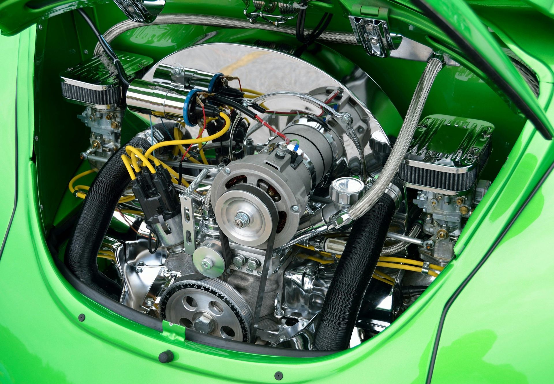 The engine of a green car is shown with the hood open