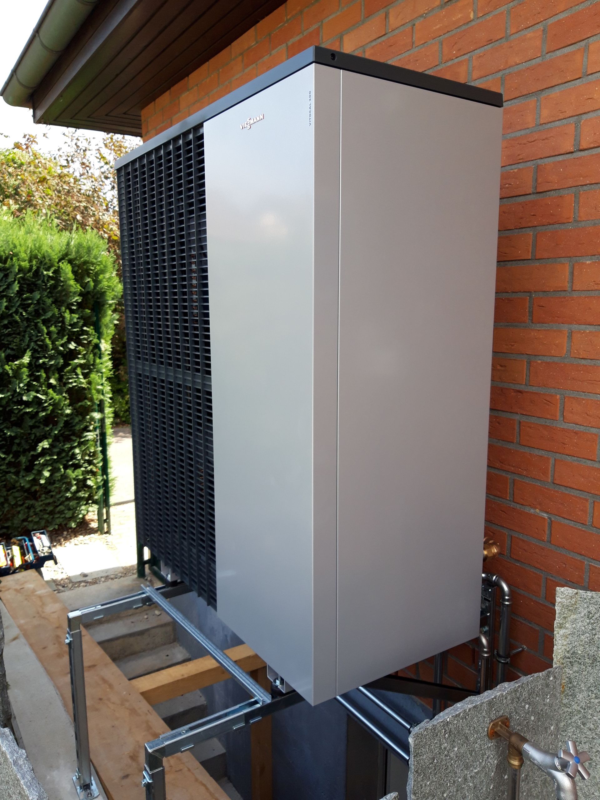 Un grand climatiseur est posé sur le côté d'un bâtiment en brique