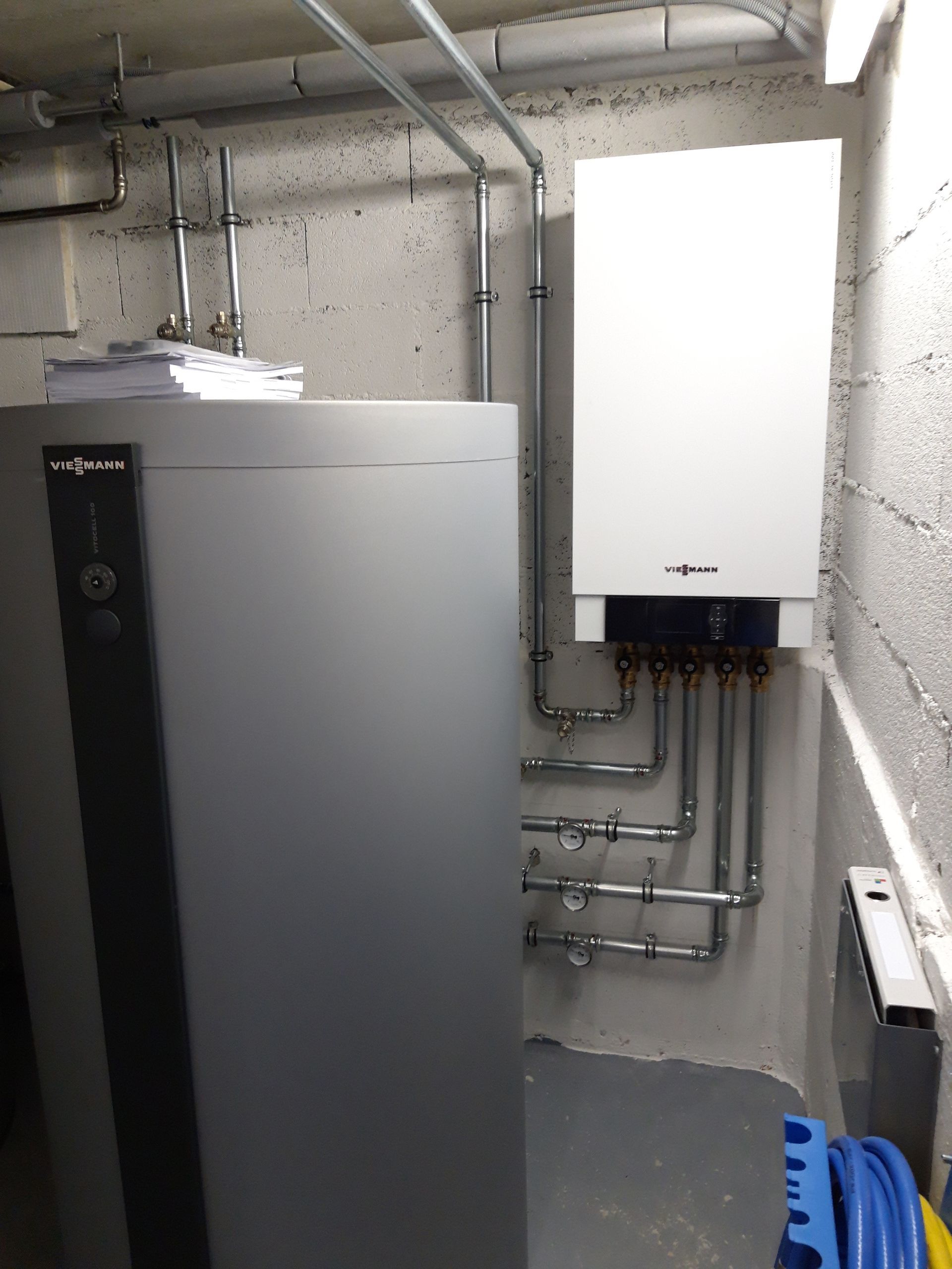 Une pièce avec une chaudière et des tuyaux au mur