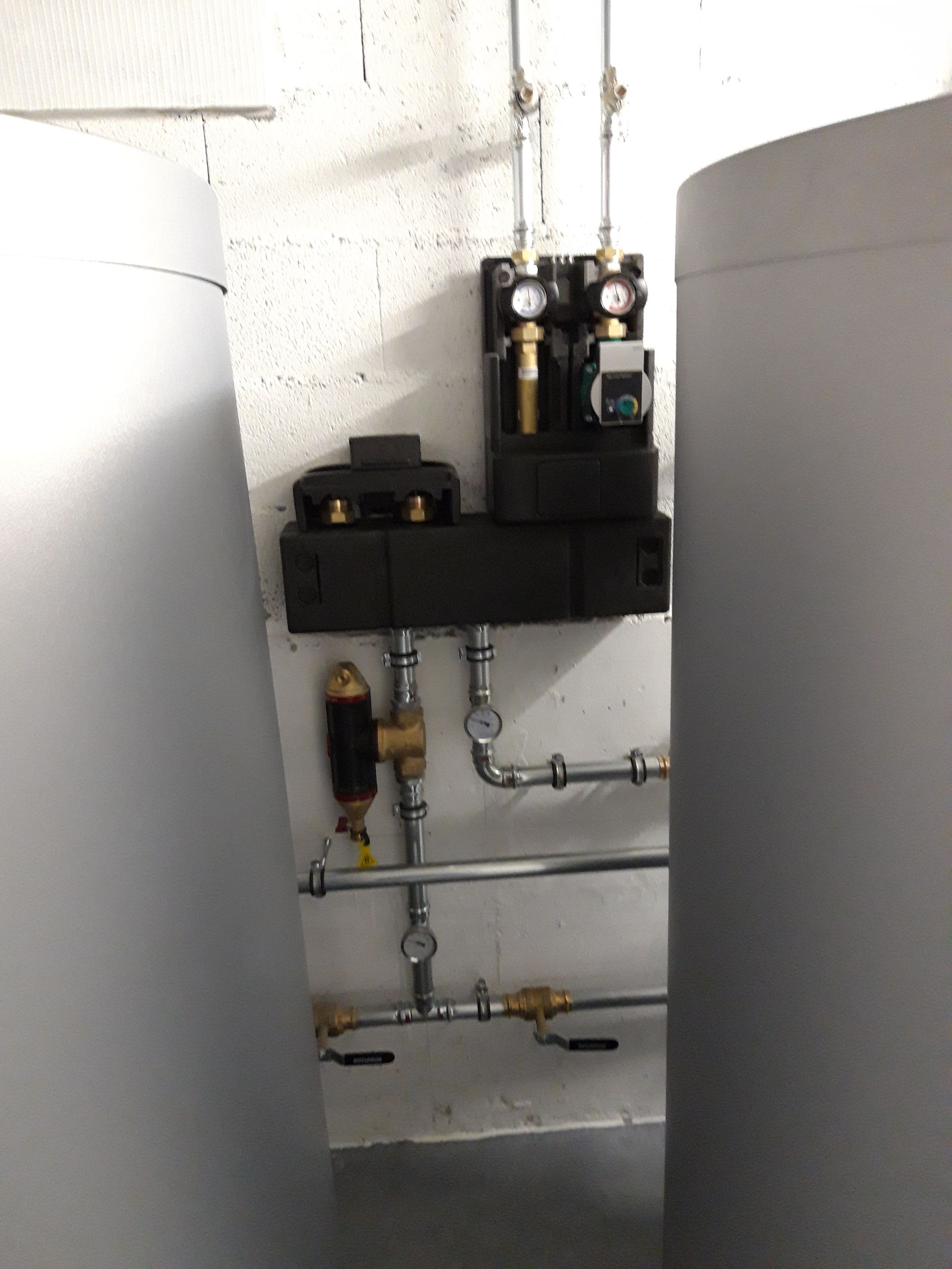 Une pièce avec beaucoup de tuyaux et de vannes au mur.