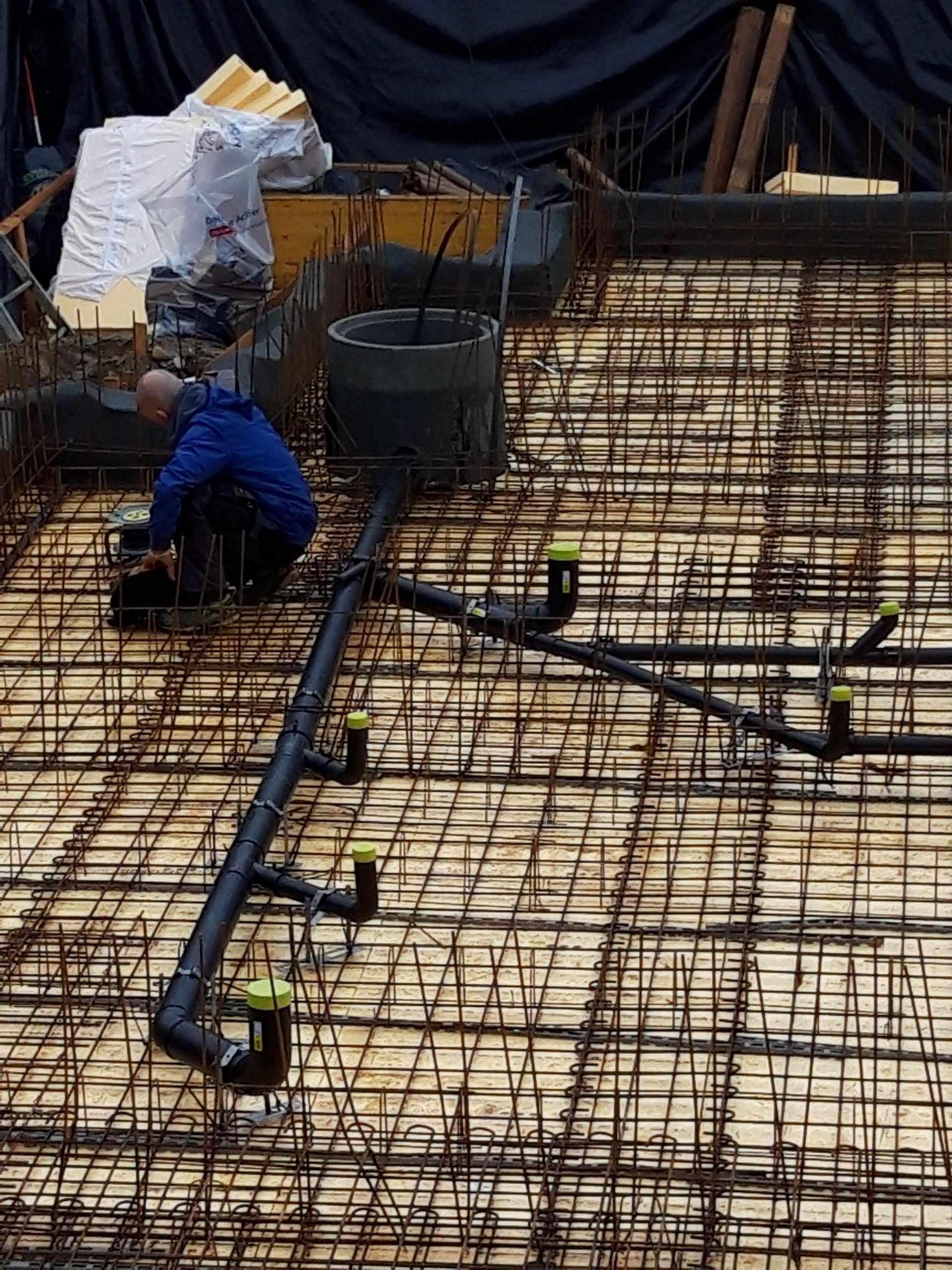 Un homme travaille sur un sol en béton avec des tuyaux.