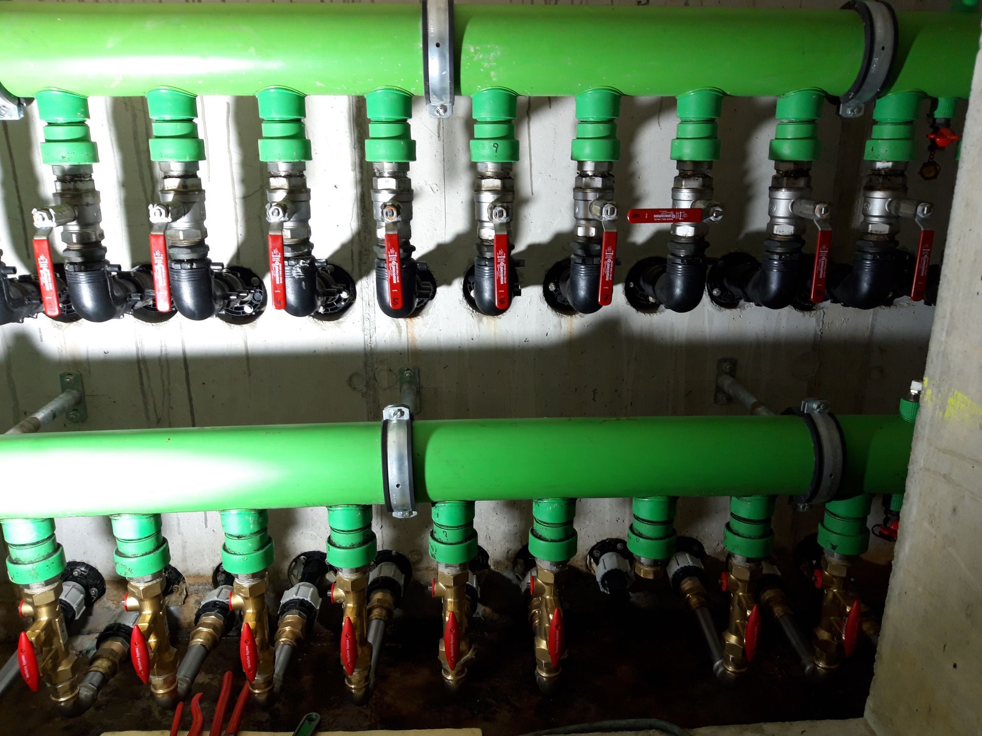 Un tas de tuyaux verts avec des valves rouges dessus
