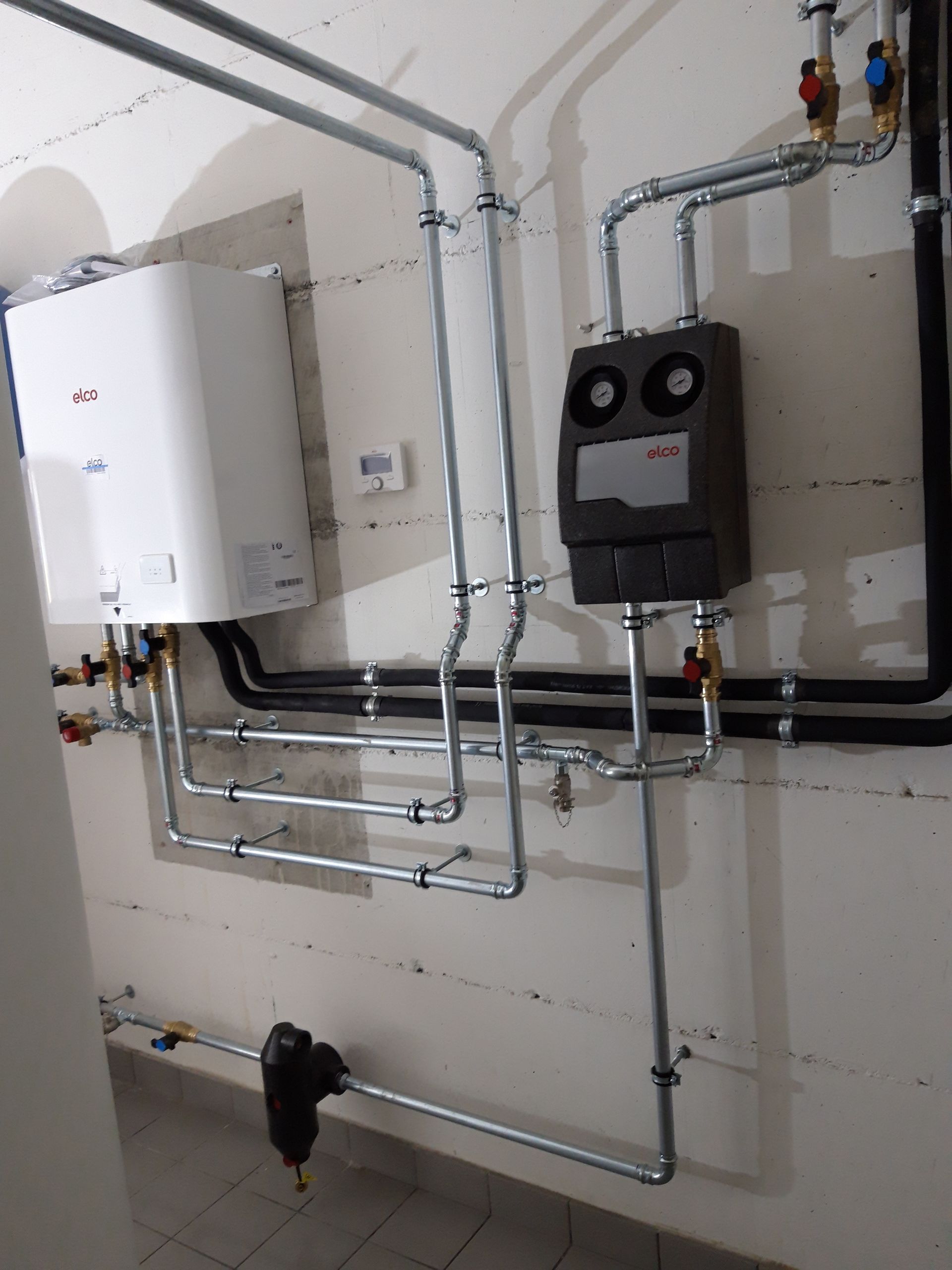 Une pièce avec des canalisations et une chaudière au mur