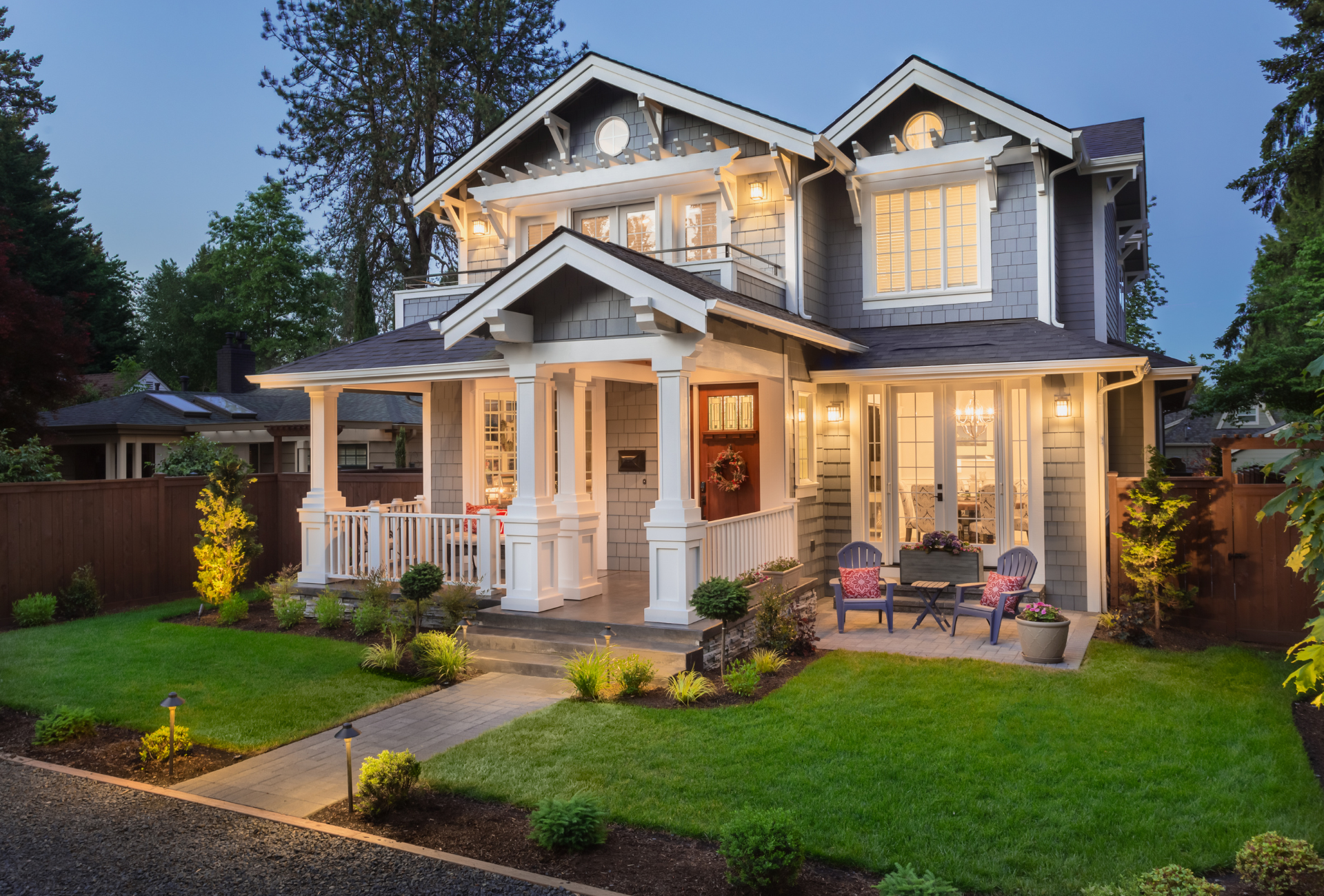 A large house is surrounded by snow and trees.