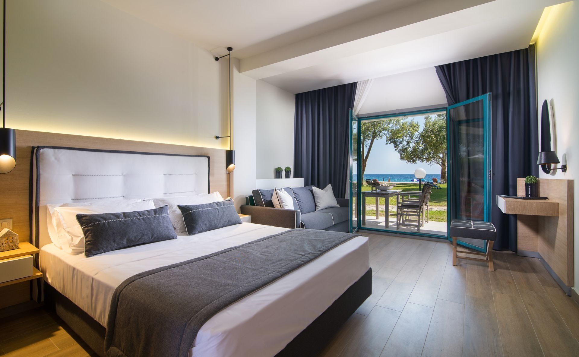 Bedroom with bed, sofa, and balcony overlooking ocean.
