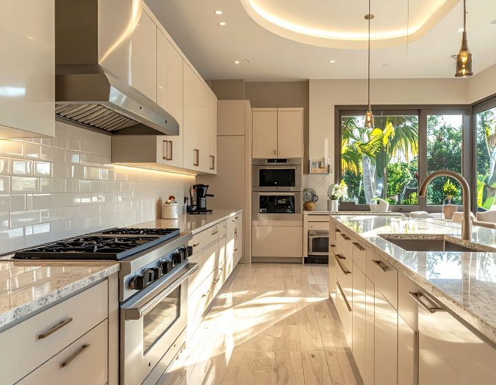 Modern kitchen with light cabinets, stainless steel appliances, and island with sink, window with lush greenery outside.