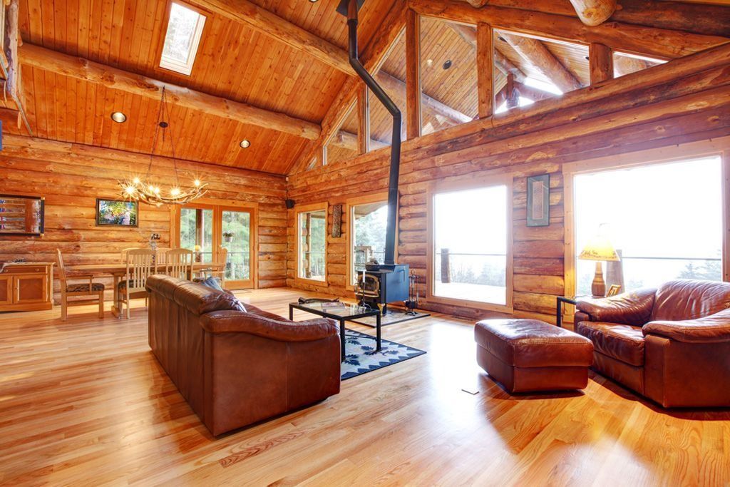 A living room in a log cabin with wooden furniture and a fireplace.
