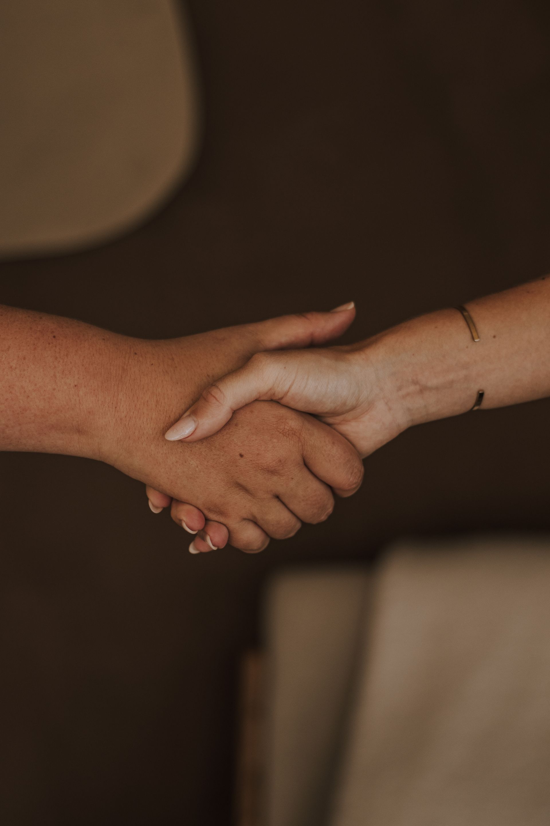 Two hands clasping in a warm handshake against a soft, blurred background
