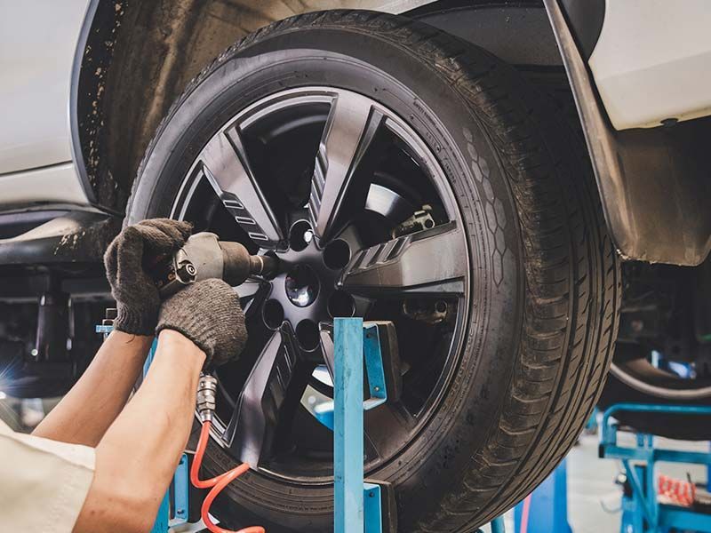 A man is changing a tire on a car with a wrench.