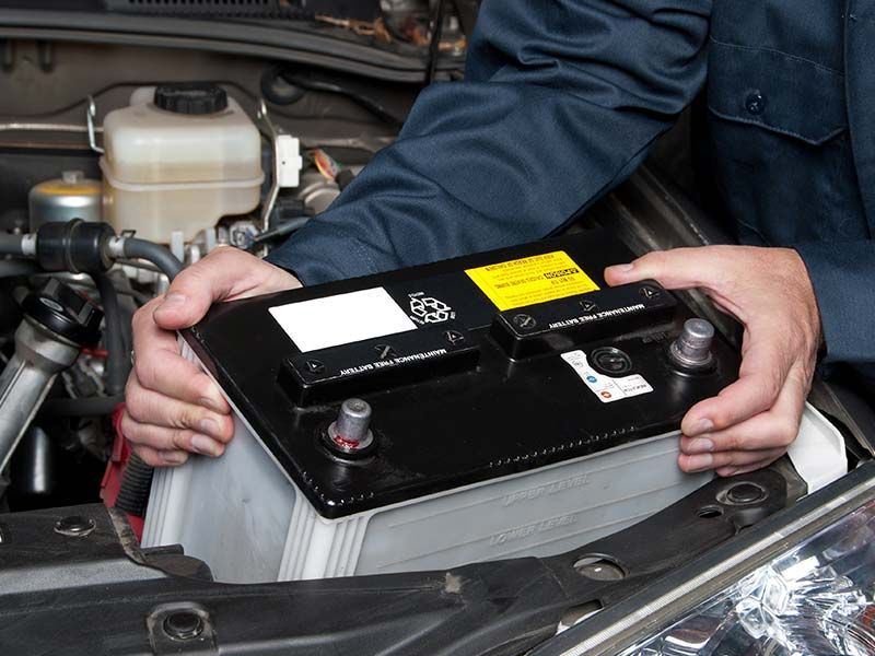 A person is holding a car battery in their hands