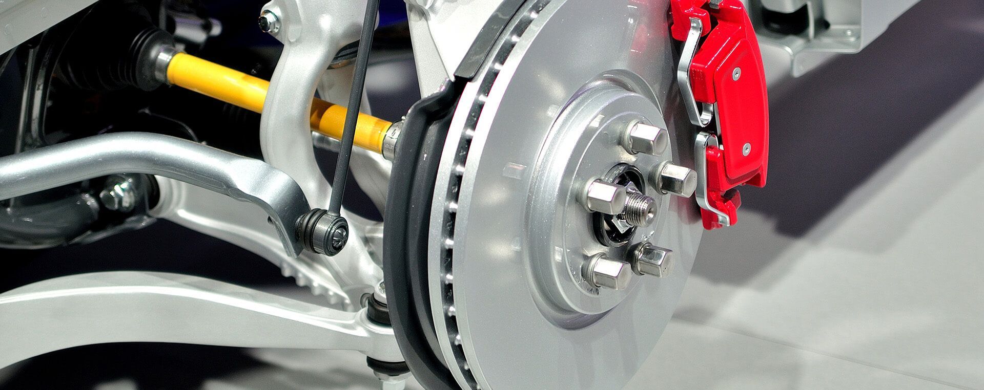 A close up of a brake disc on a car with a red brake caliper.