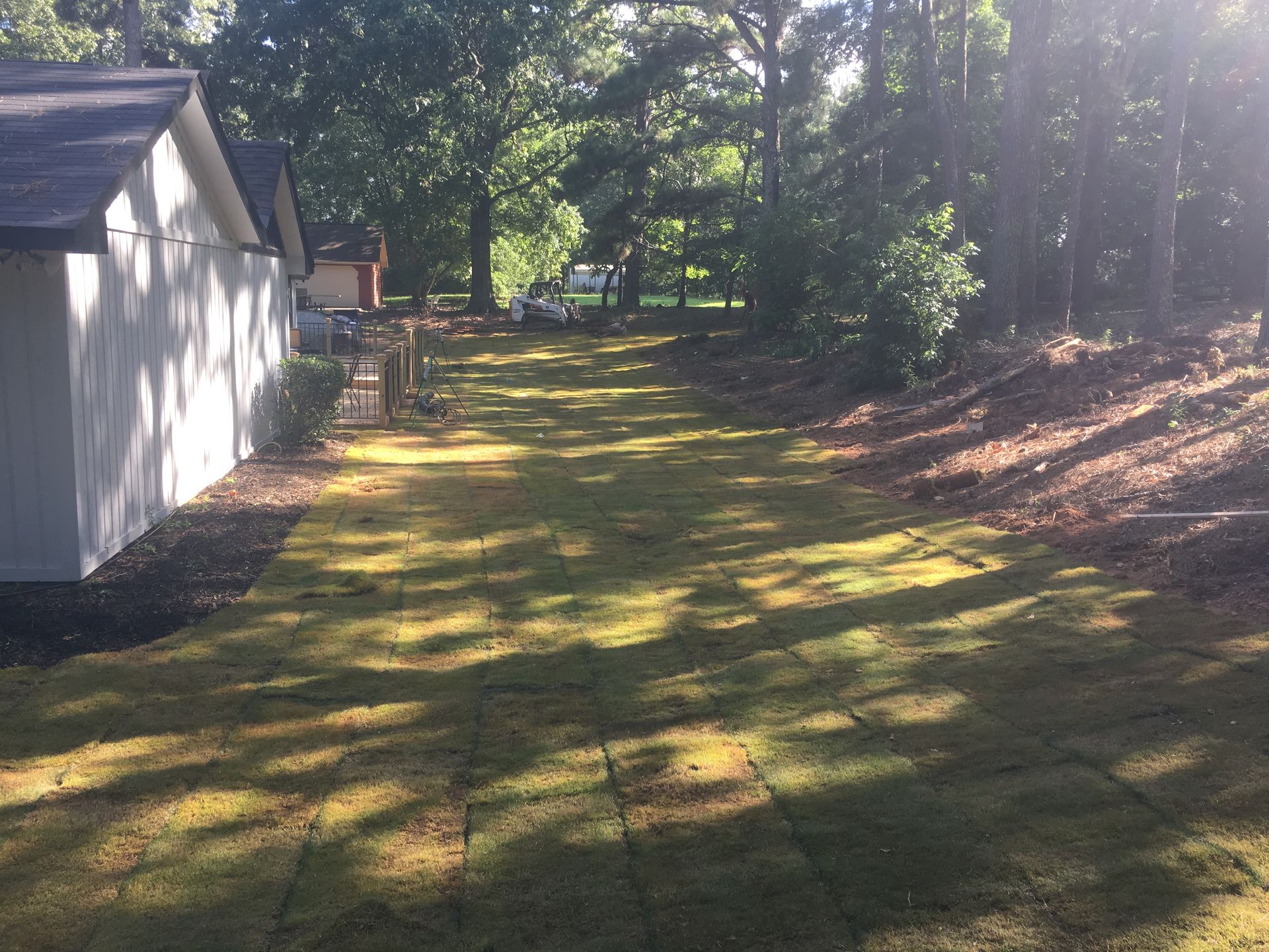 A driveway with a lot of grass and trees in the background