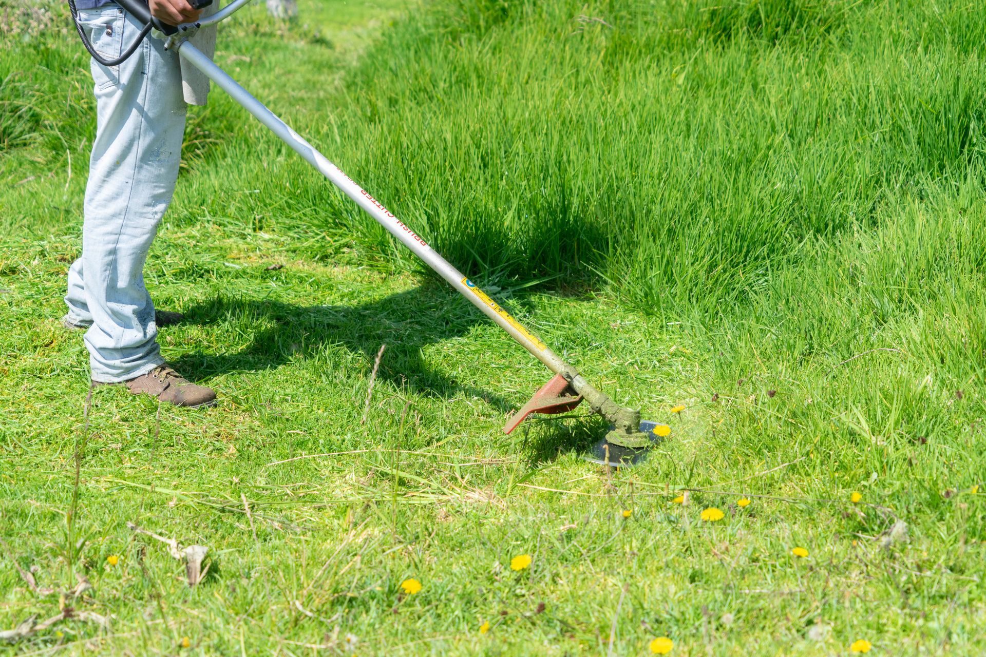 A man is mowing the grass with a lawn mower.