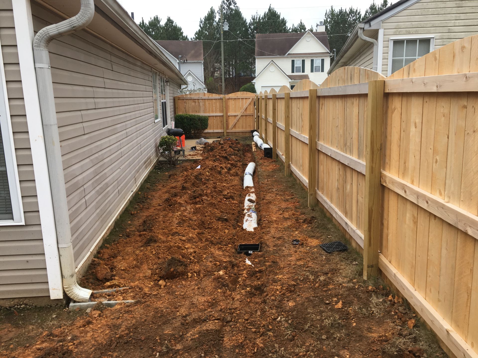 A wooden fence surrounds a dirt area in front of a house