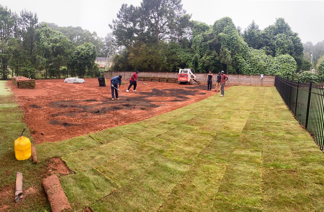 A group of people are working on a lush green lawn.