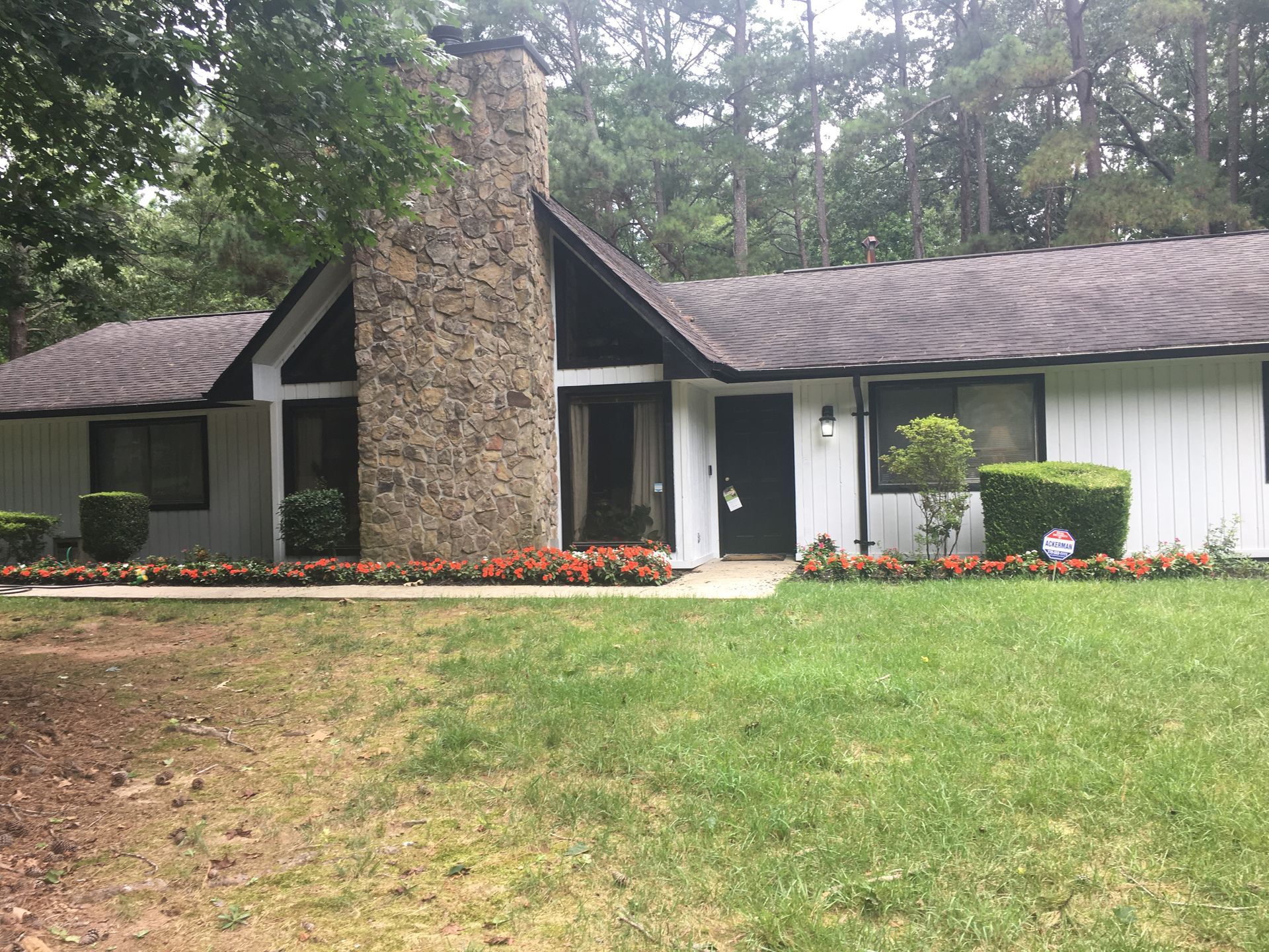 A white house with a brown roof and a stone chimney