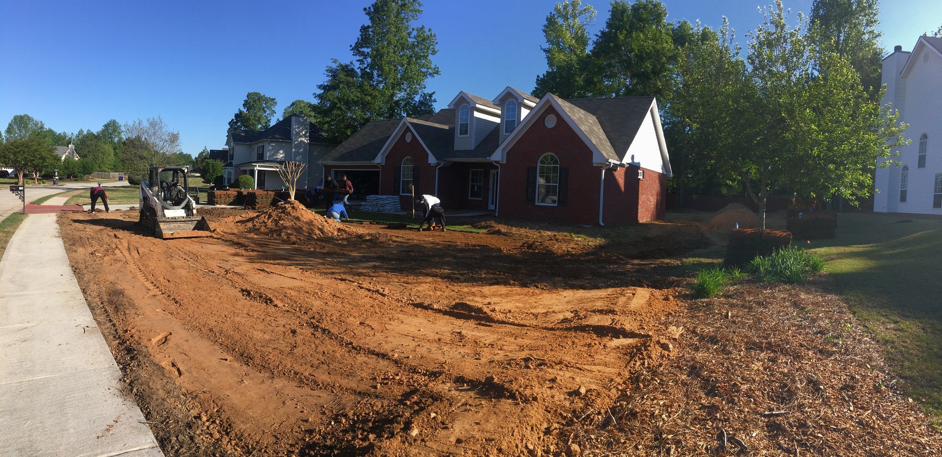 A couple of tractors are working on a dirt road.