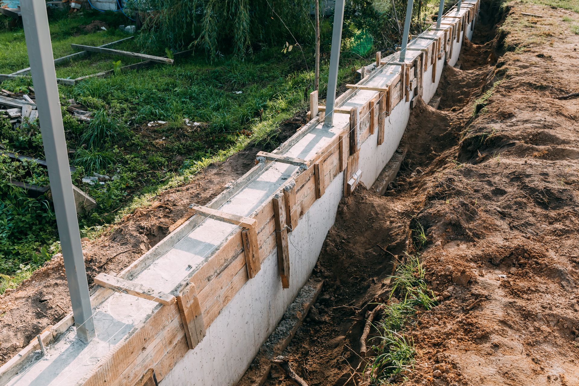 Construction of a concrete retaining wall in a trench, with wooden supports and metal posts.