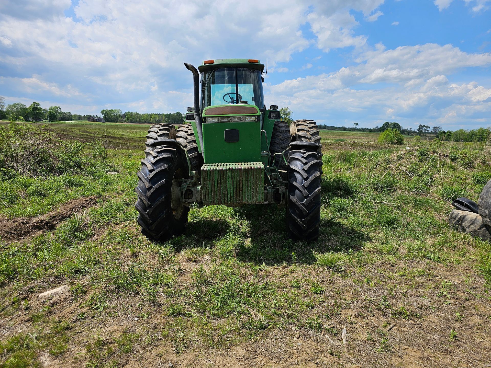 A green tractor is parked in a grassy field.