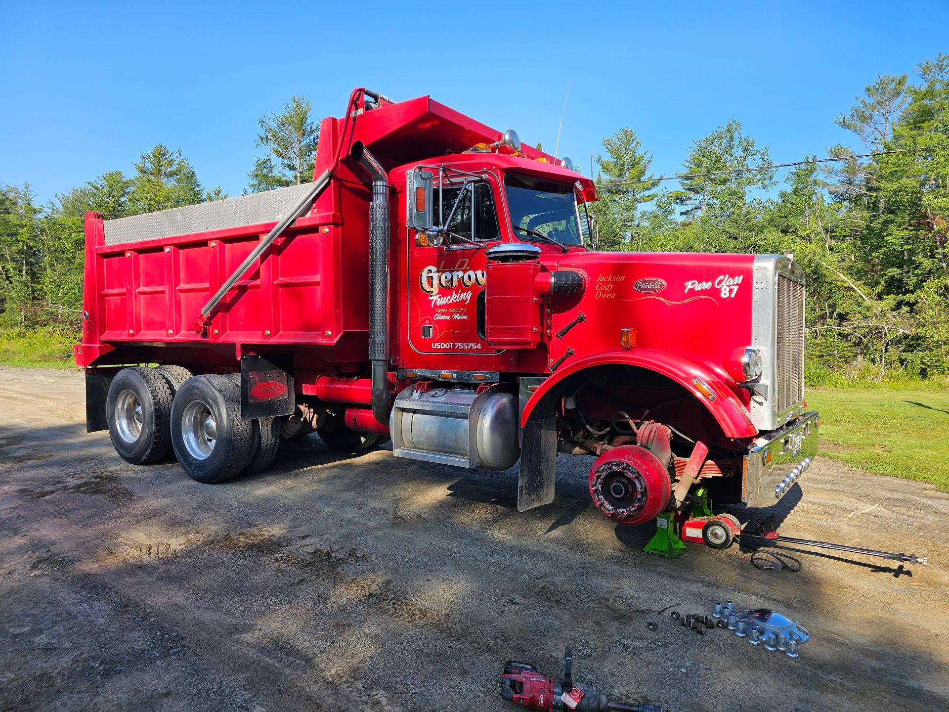 A red dump truck is parked on the side of a dirt road.