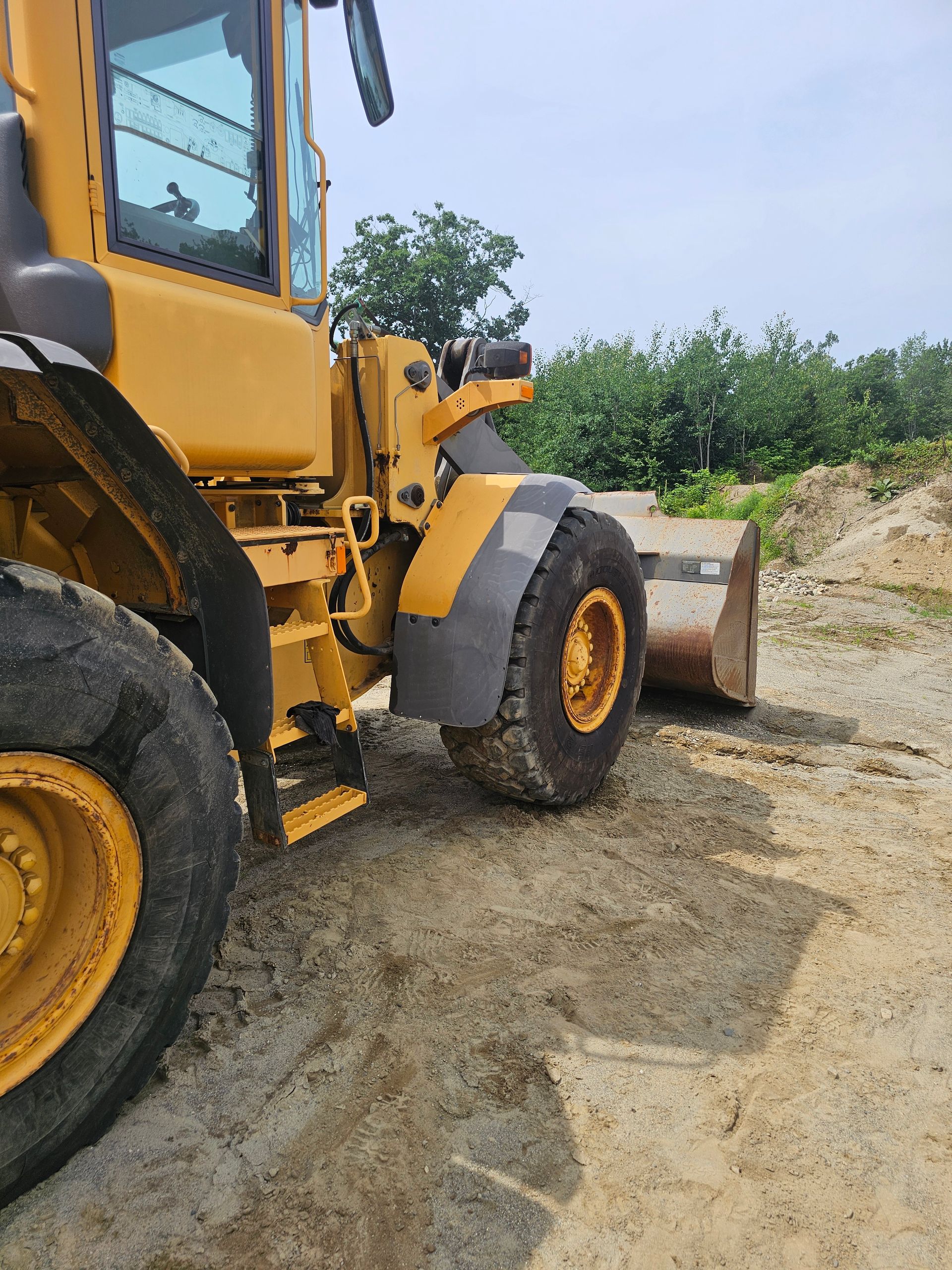 A yellow bulldozer is parked on a dirt road.