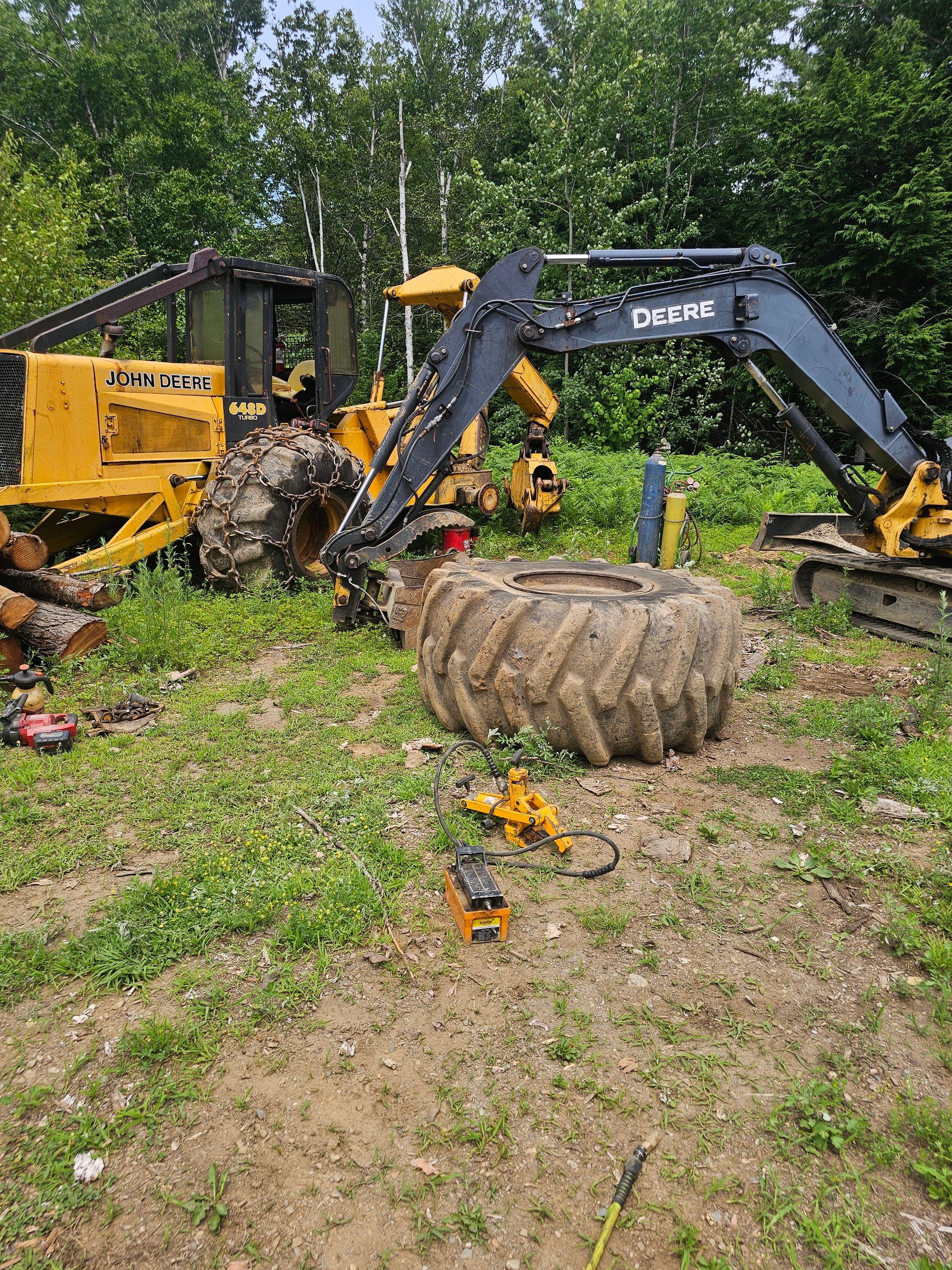 A large tire is sitting on the ground next to a tractor in a field.