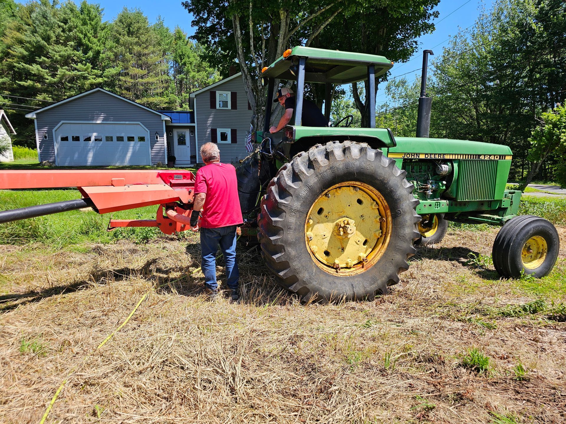 A man is standing next to a green john deere tractor in a field.