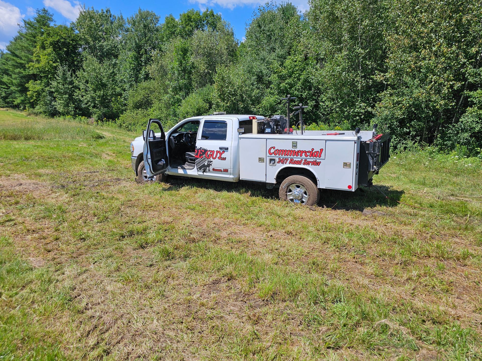 A white tow truck is parked in a grassy field.