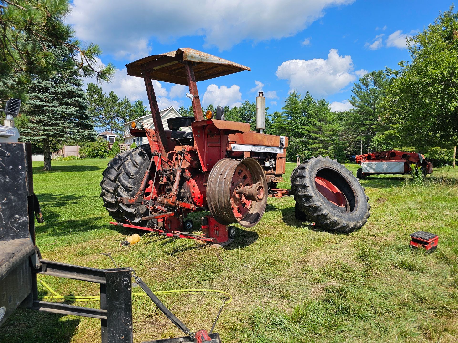 An old red tractor is sitting in a grassy field.