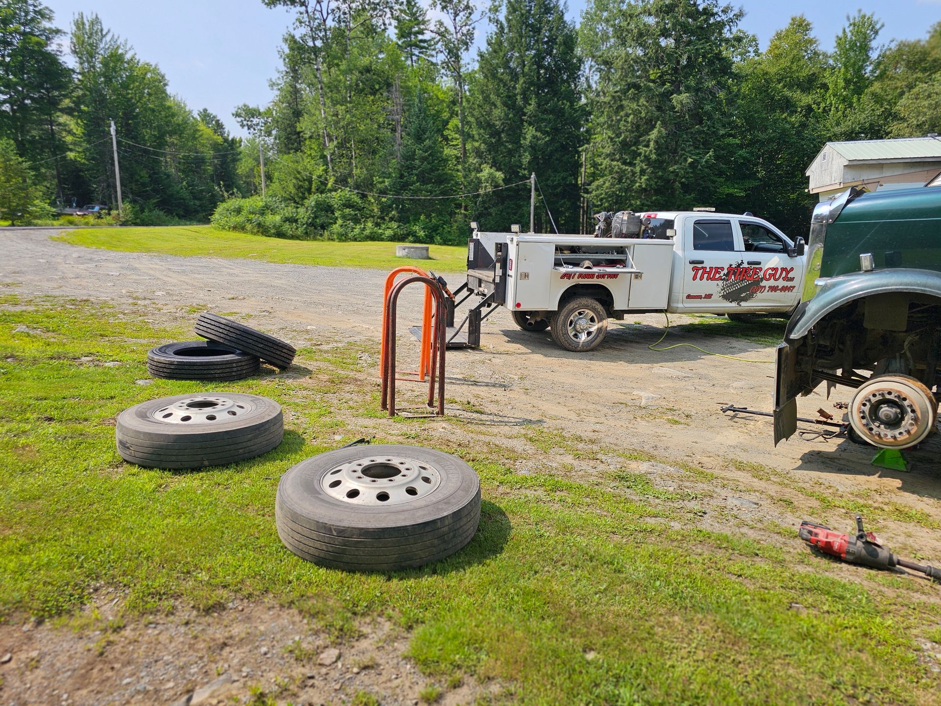 A tow truck is parked in a grassy field next to a bunch of tires.