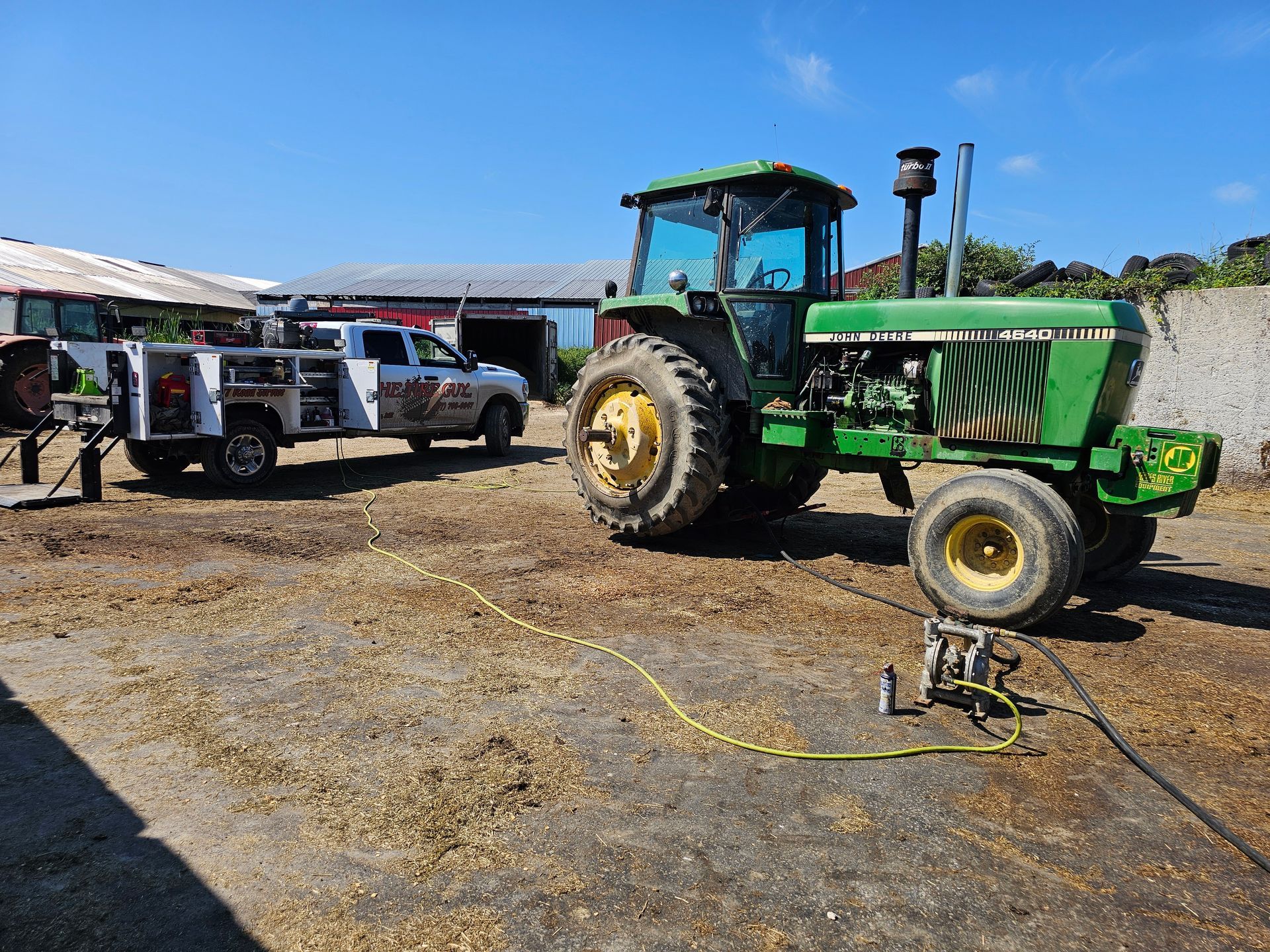 A green tractor is parked next to a white truck.