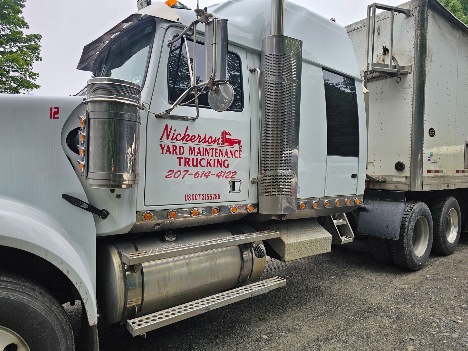 A white truck with a red logo on the side is parked in a parking lot.