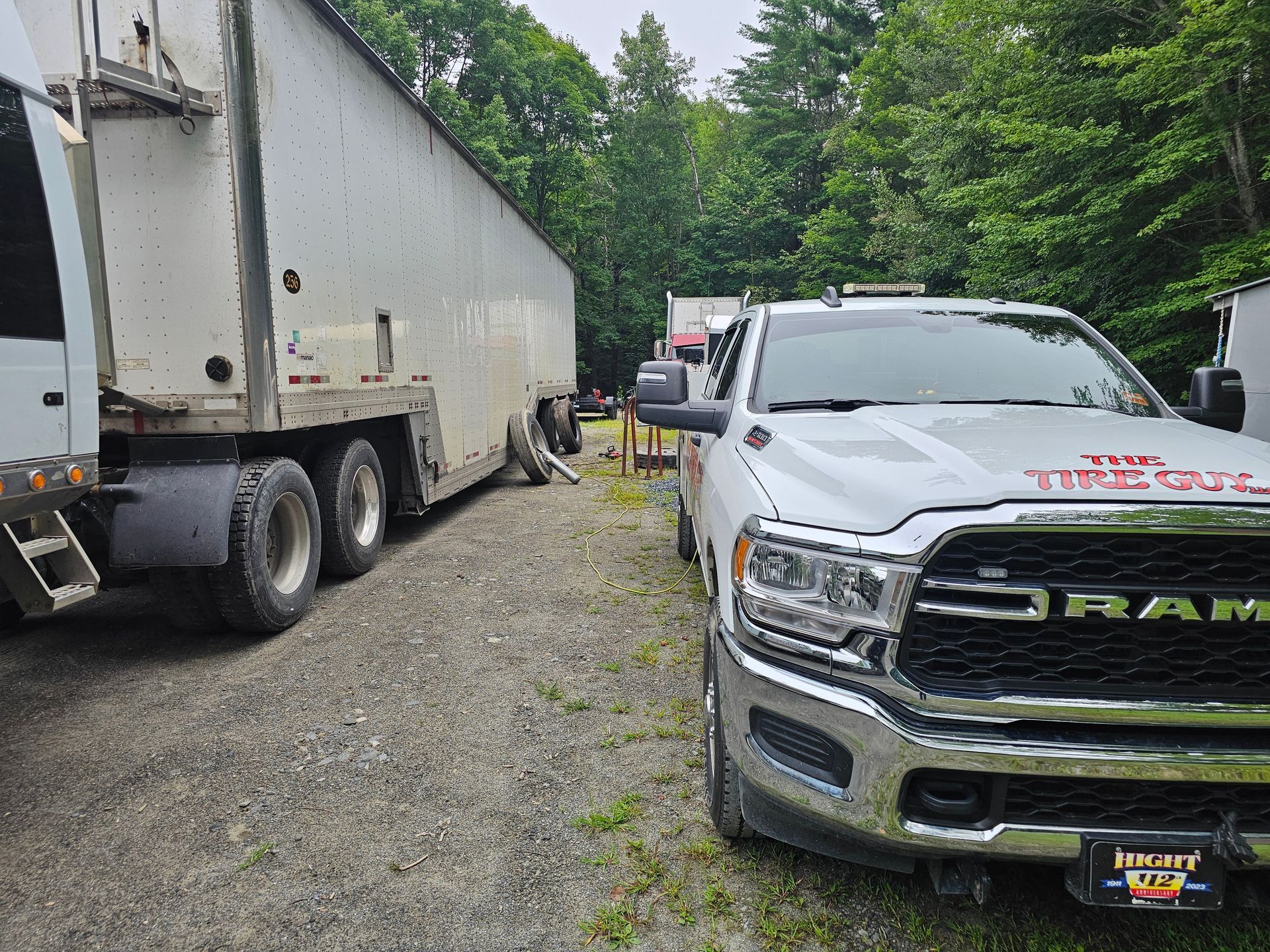 A ram truck is parked in a gravel lot next to a semi truck.