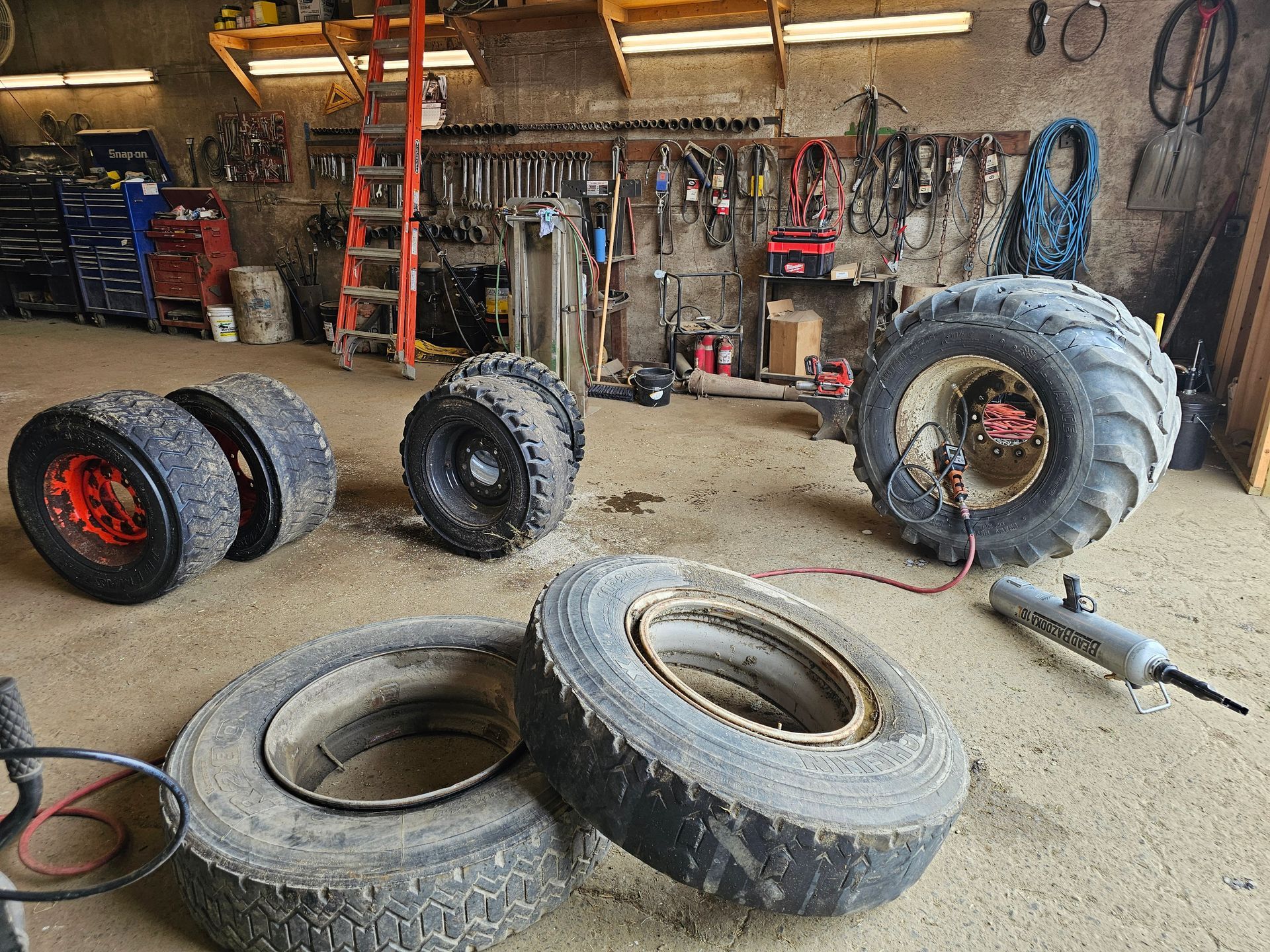A bunch of tires are sitting on the ground in a garage.