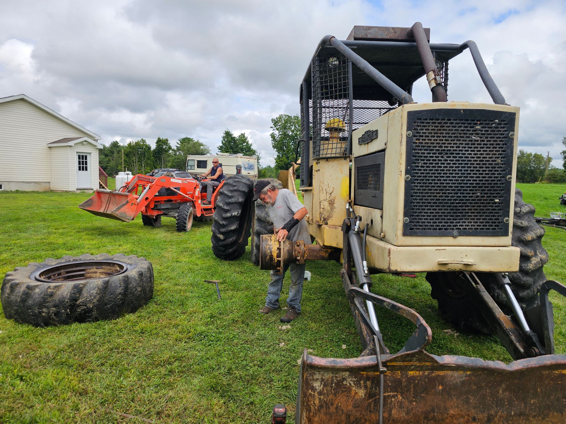 A man is working on a tractor in a grassy field.