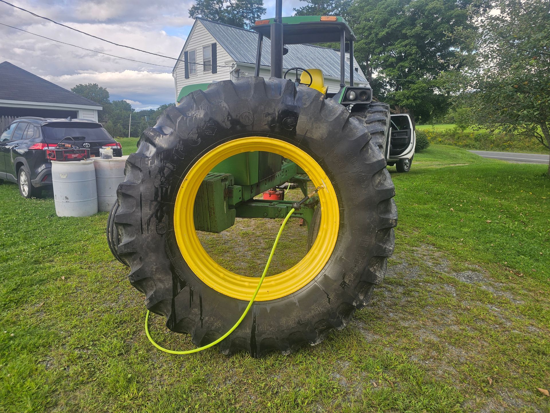 A large tire with a yellow rim is sitting on the ground next to a tractor.