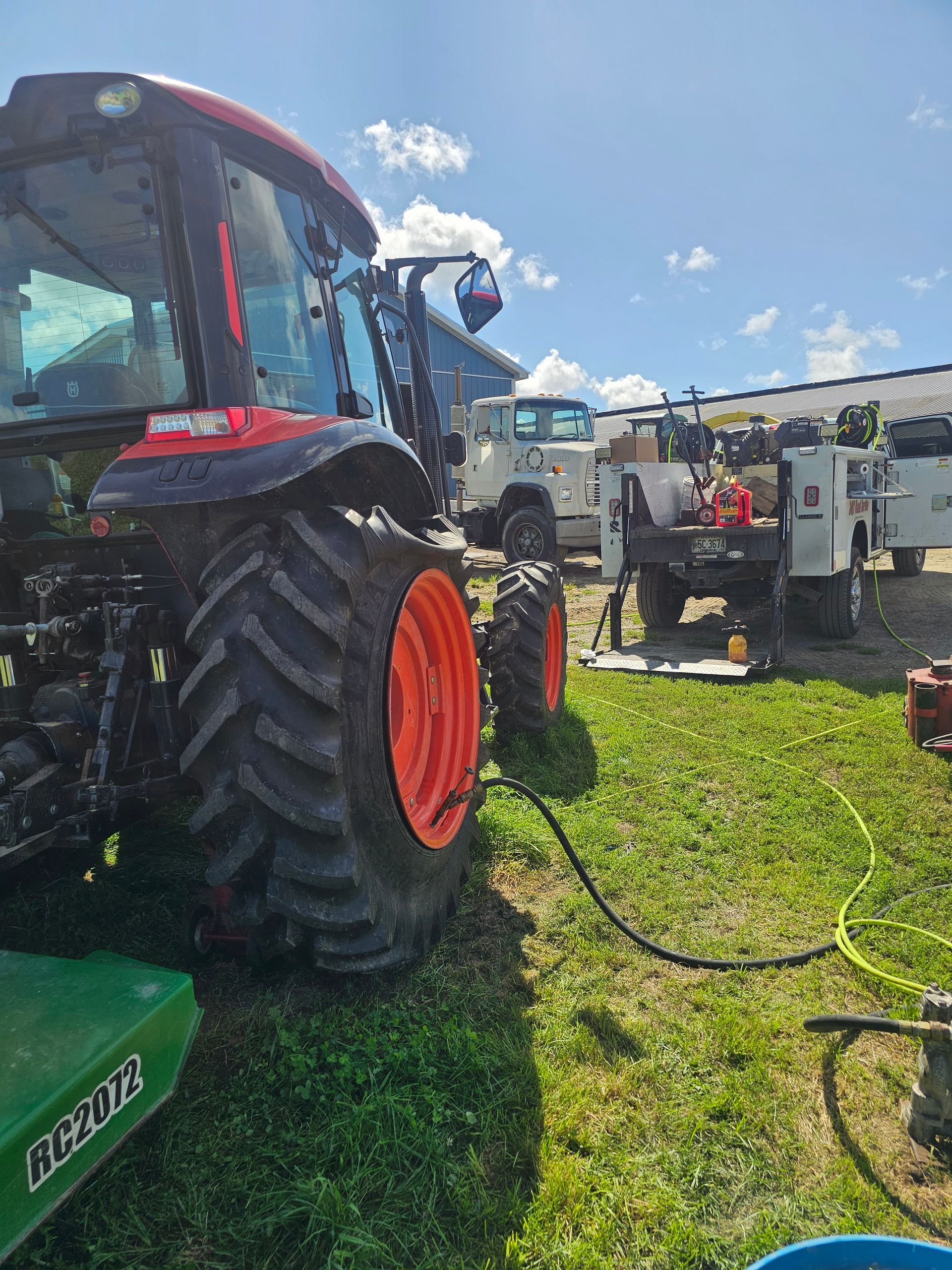 A tractor is parked in a grassy field next to a truck.