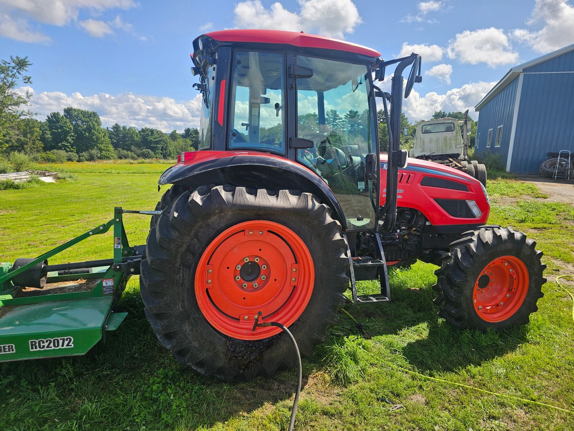 A red and orange tractor is parked in a grassy field.