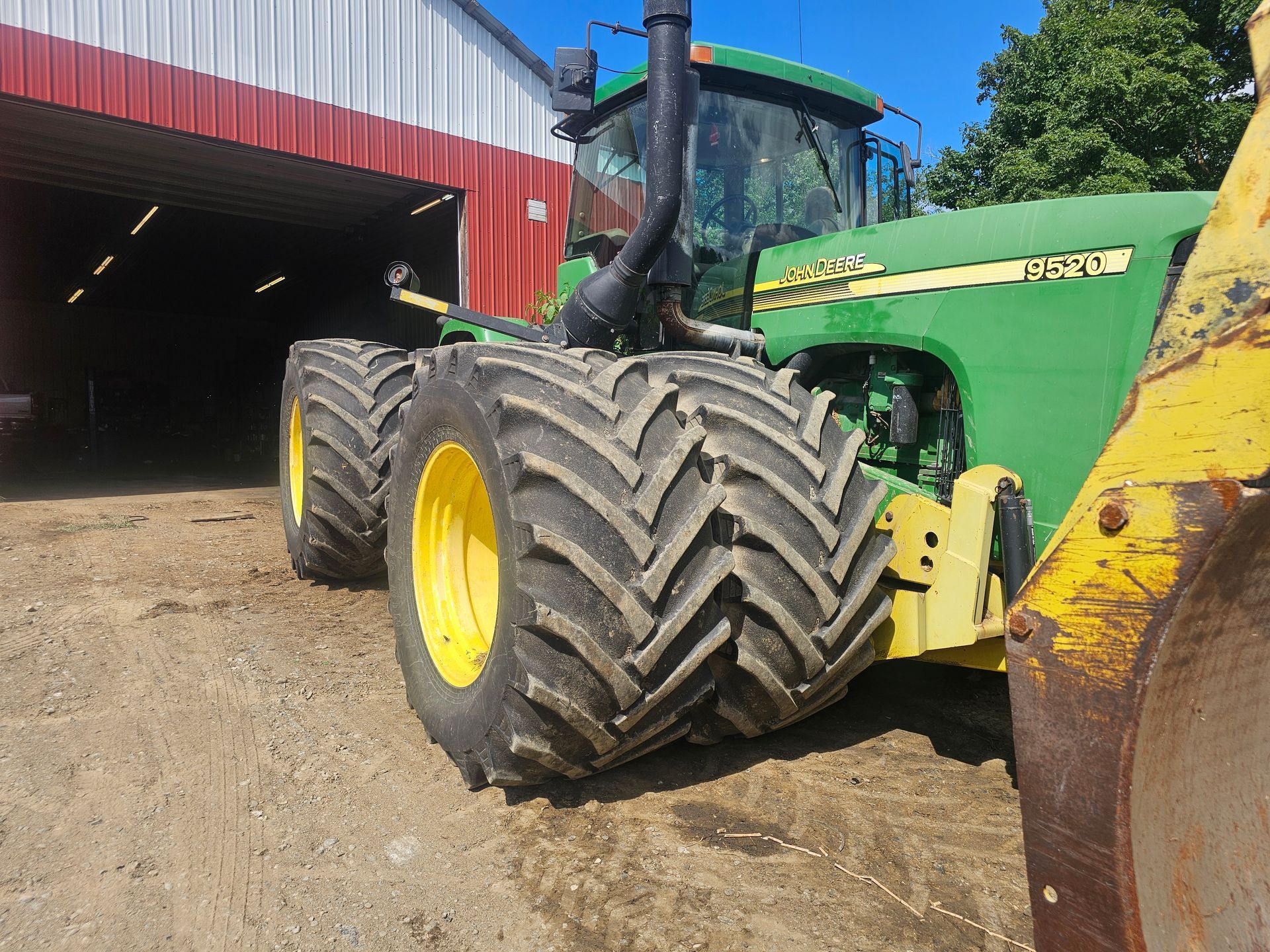 A green john deere tractor is parked in front of a red and white building.