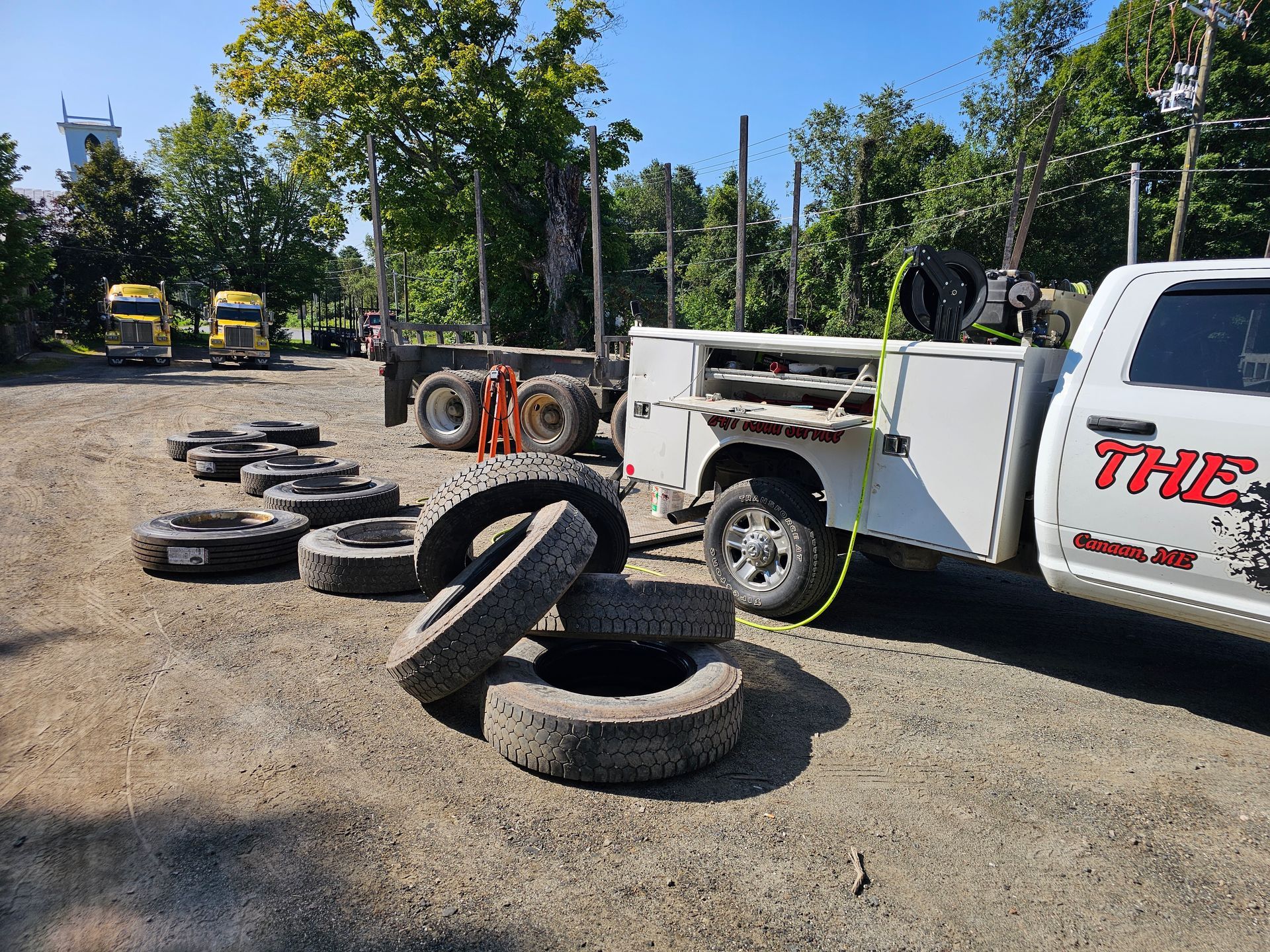 A white truck is parked next to a pile of tires.