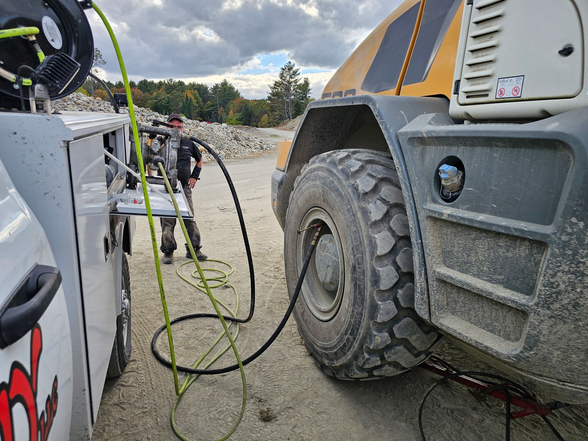 A man is standing next to a truck that is being fueled.