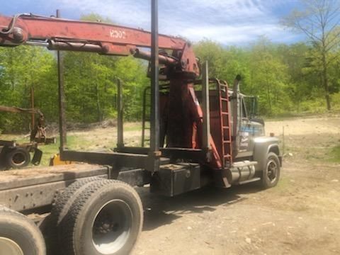 A truck with a crane attached to it is parked in a dirt field.