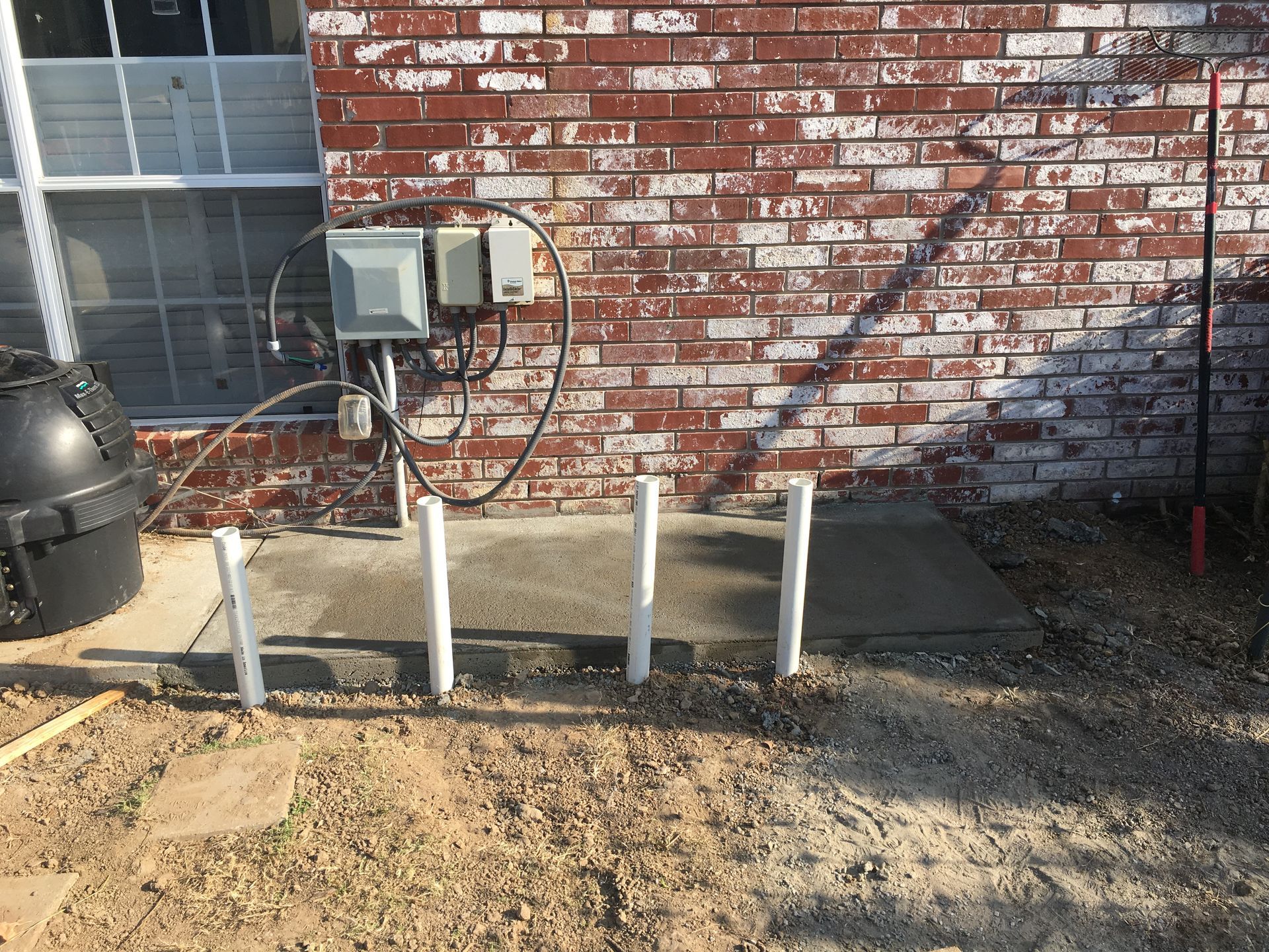 A brick wall with a concrete walkway in front of it.
