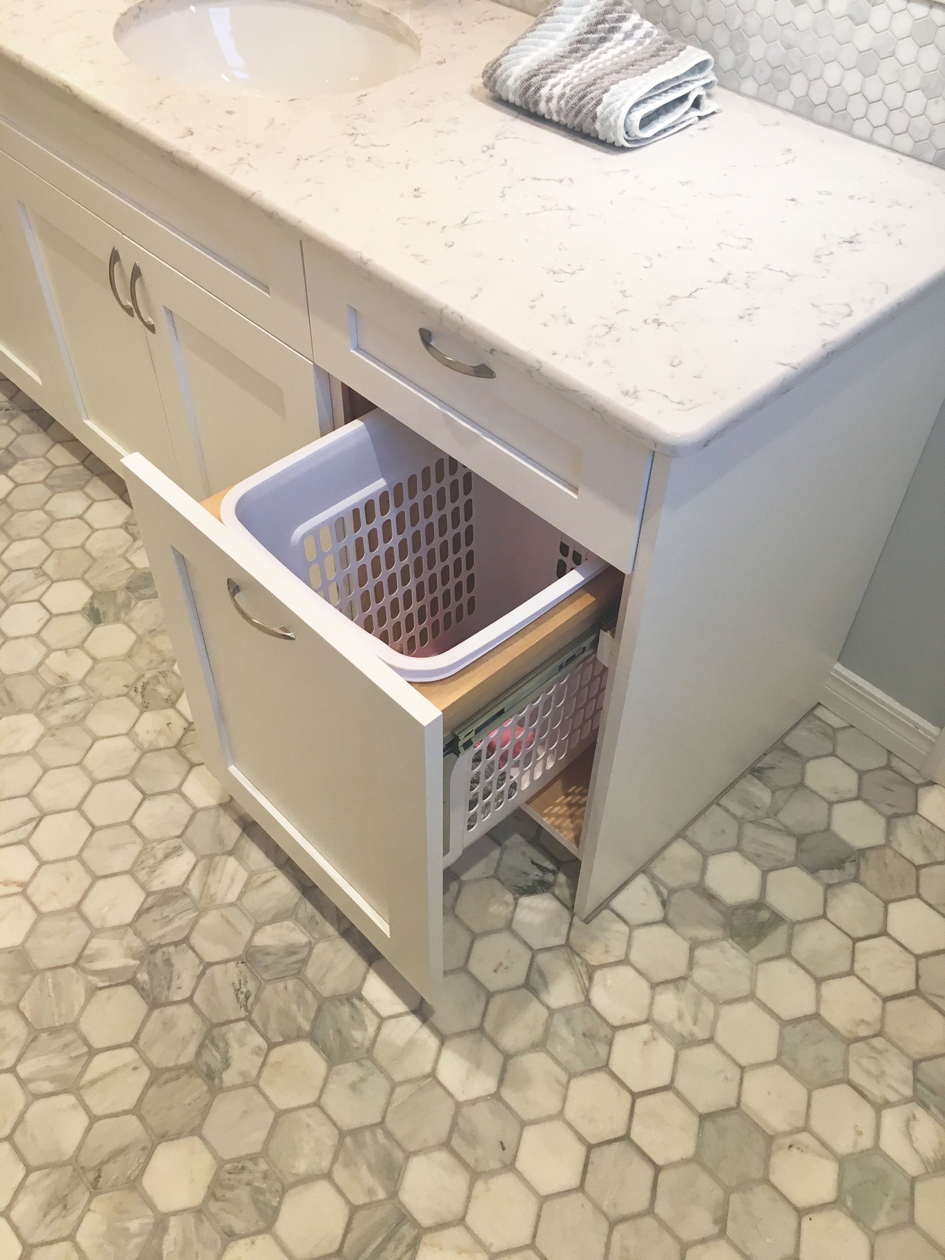A bathroom vanity with a laundry basket in the drawer