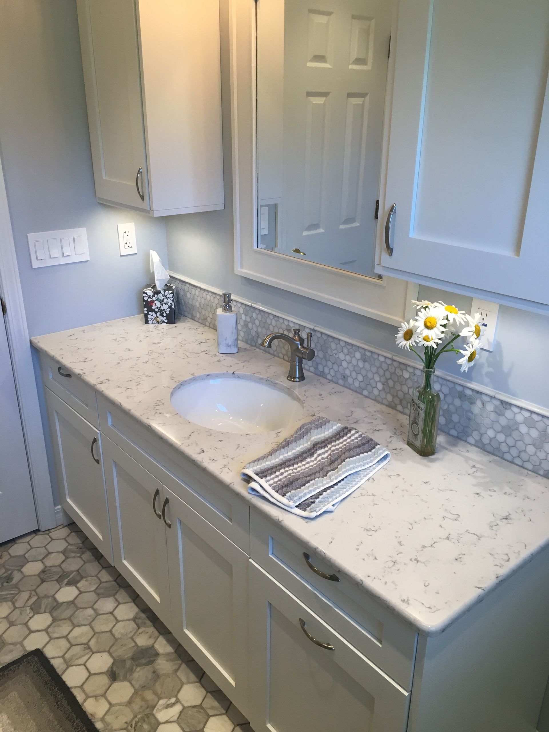 A bathroom with a sink , cabinets , and a mirror.