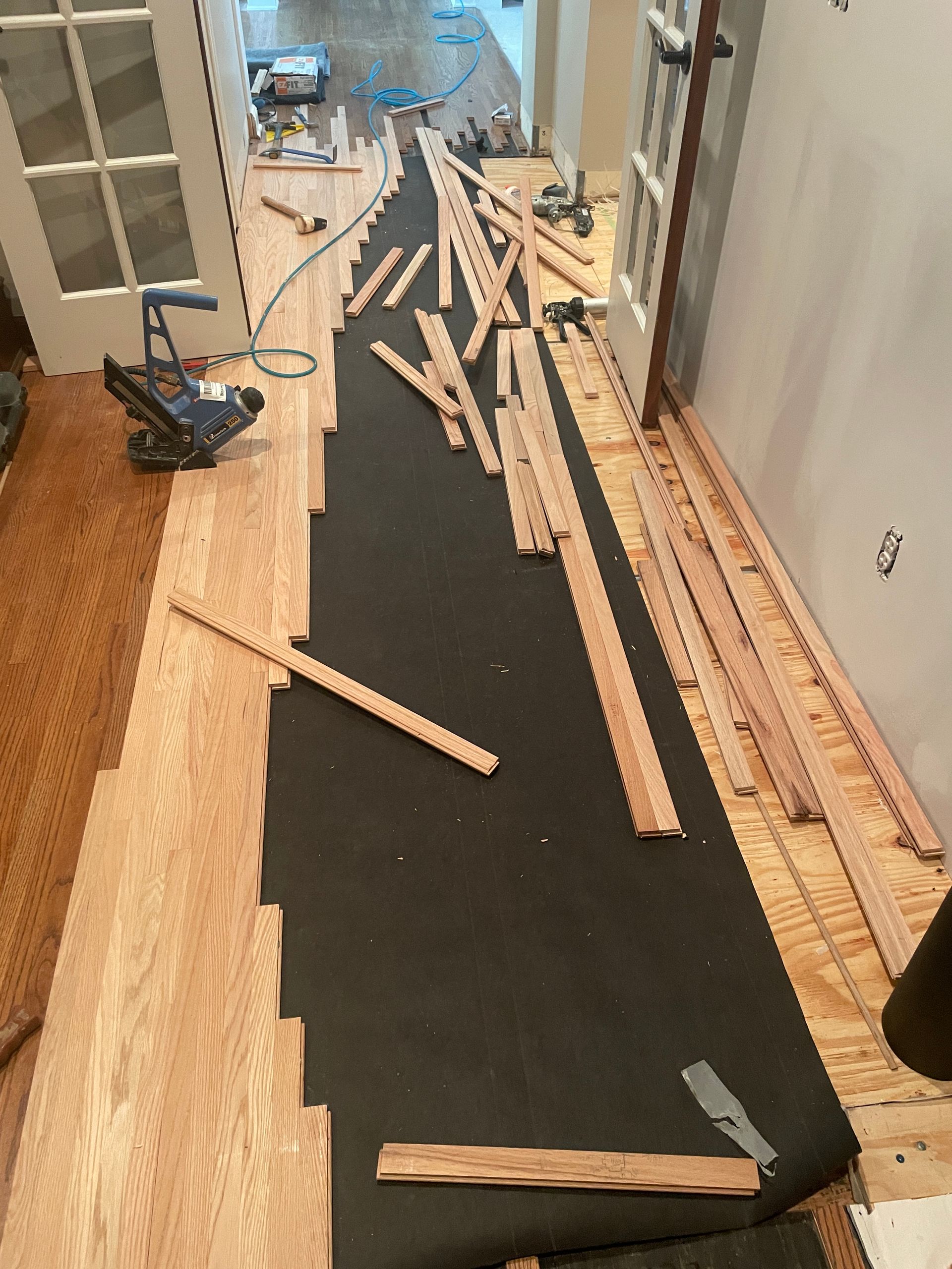 A wooden floor is being installed in a hallway