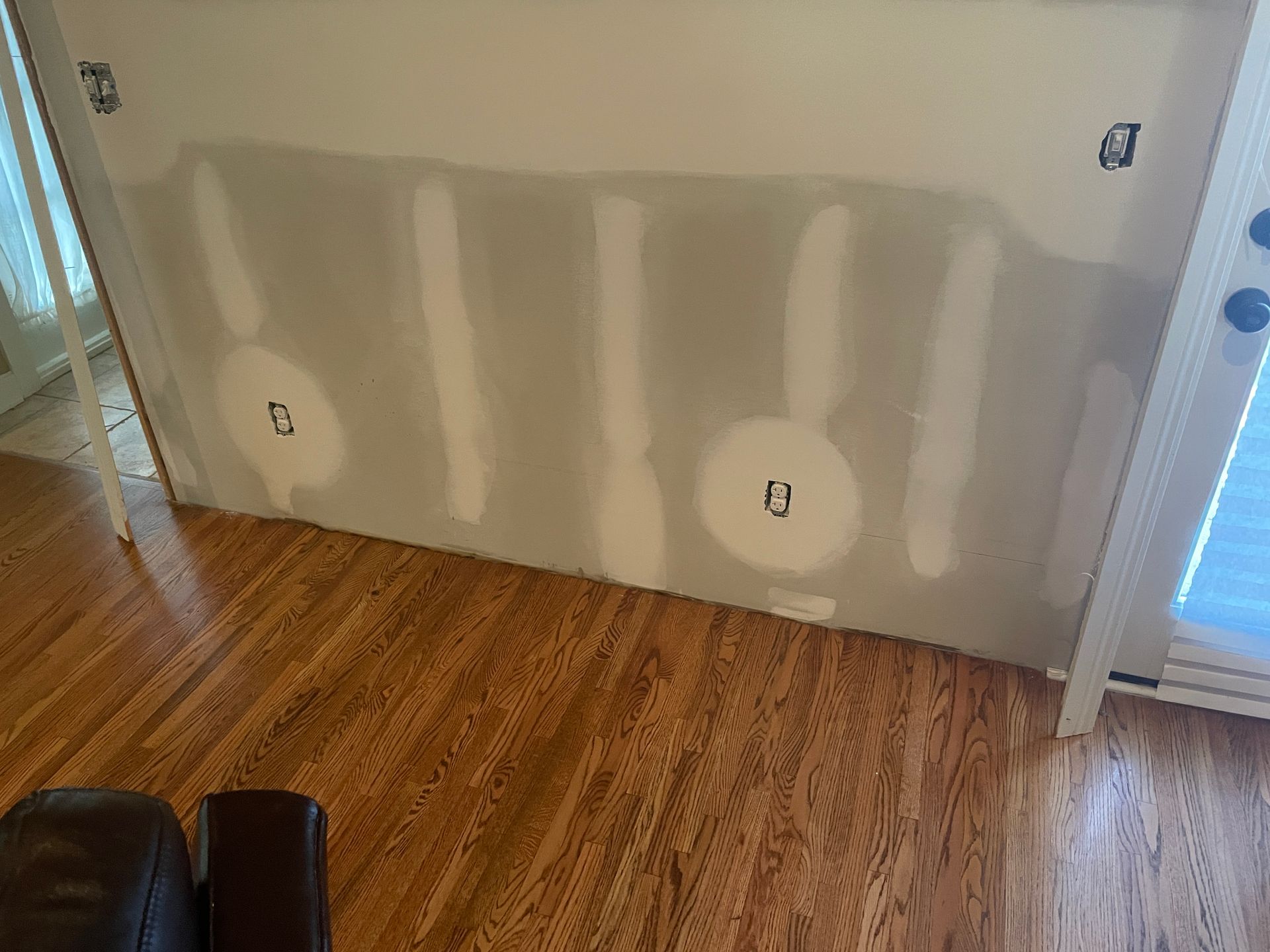 A living room with hardwood floors and a white wall.