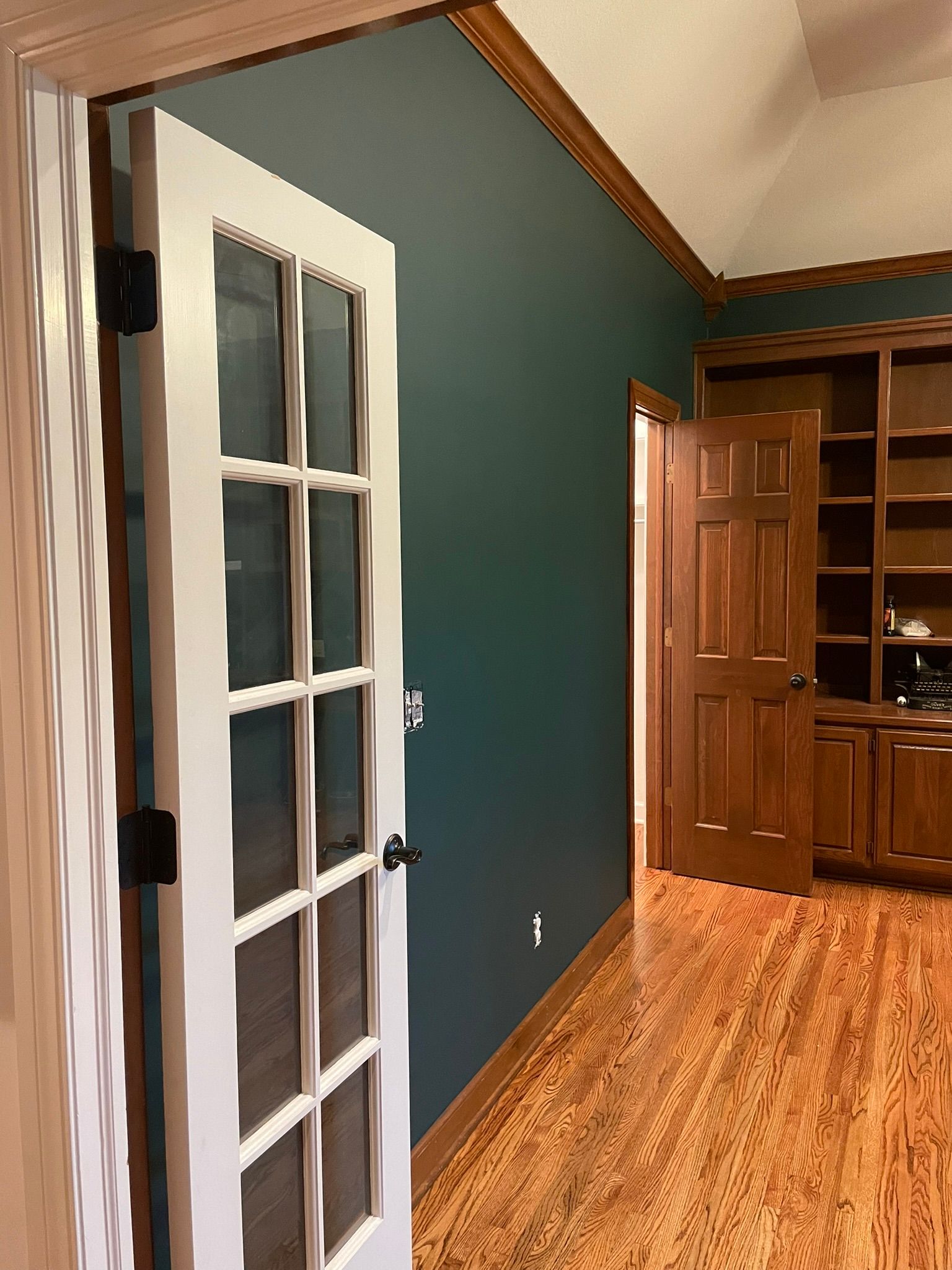 A french door is open in a room with hardwood floors.