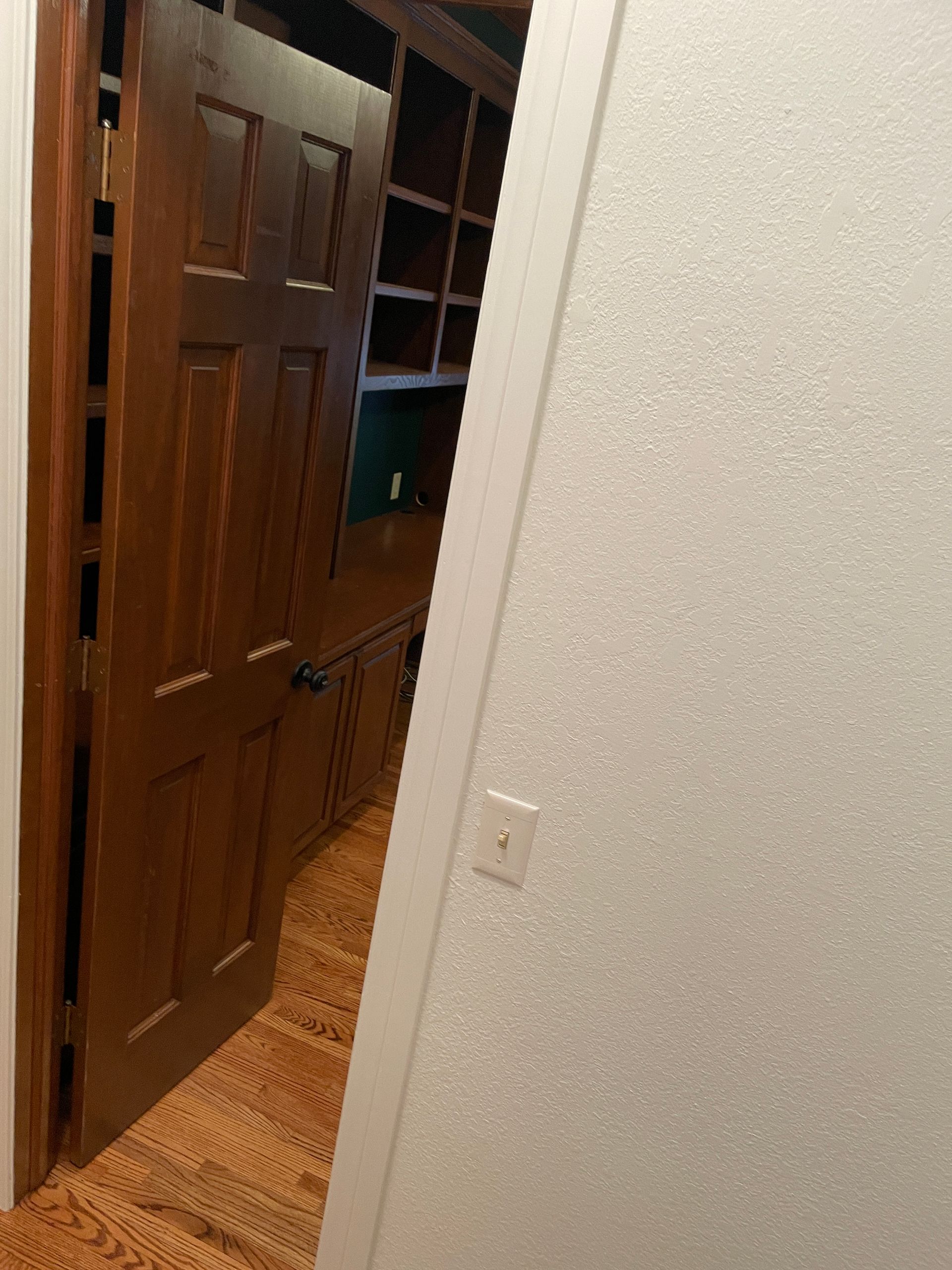 A hallway with a wooden door and a white wall.